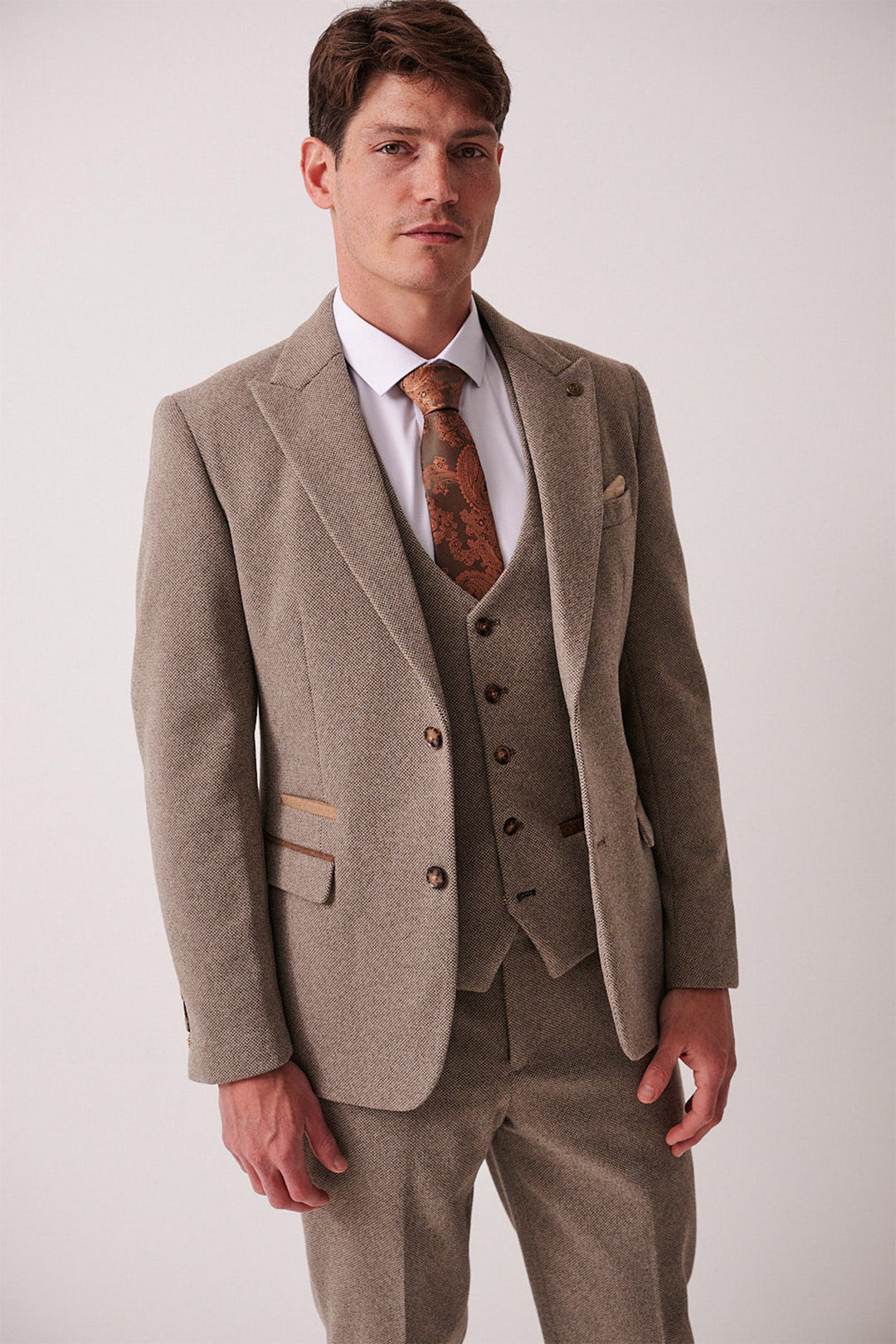 A man stands facing forward wearing the marcdarcy HAYDEN - Tan Crossweave Blazer, paired with a white shirt and patterned brown tie, posing against a plain light background.