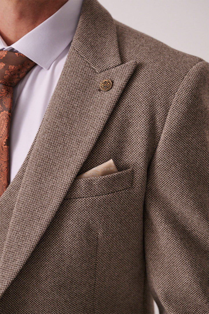 Close-up of a man wearing the marcdarcy HAYDEN Tan Crossweave Three Piece Suit with a white dress shirt, patterned brown tie, beige pocket square, and a round lapel pin.