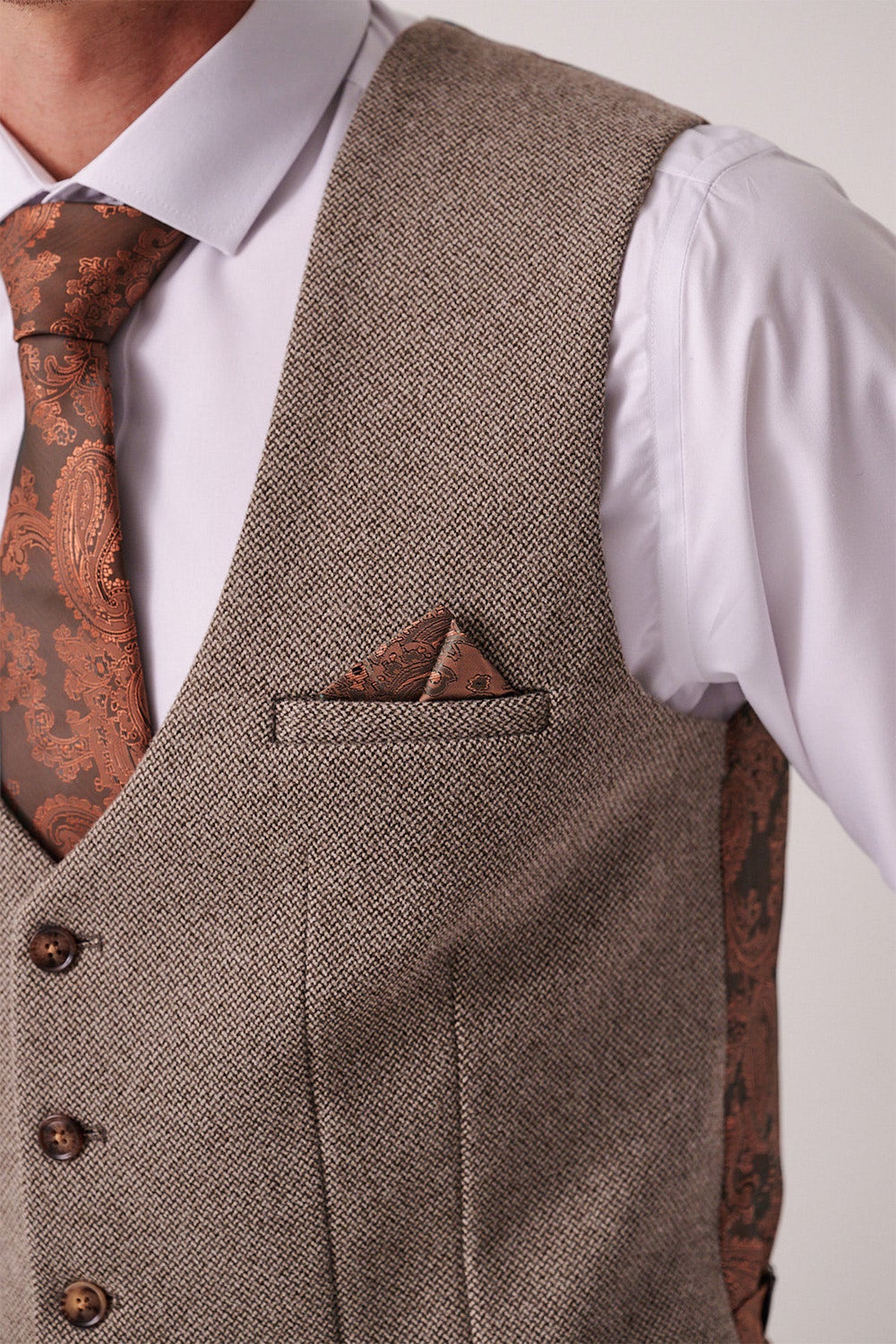 A person wears the Marc Darcy HAYDEN Tan Crossweave Waistcoat over a white shirt, styled with a brown paisley tie and matching pocket square. The image, cropped to the upper torso, highlights the slim fit and elegant design.
