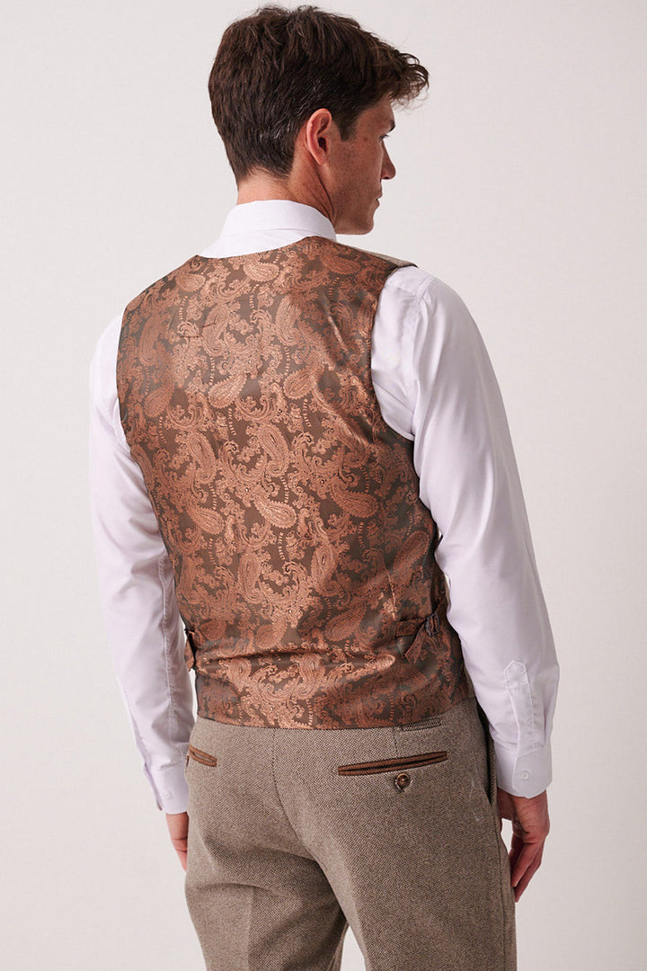 A man faces away, wearing the marcdarcy HAYDEN tan crossweave three piece suit, featuring a tailored waistcoat over beige trousers with buttoned back pockets, embodying the refined style of classic menswear.