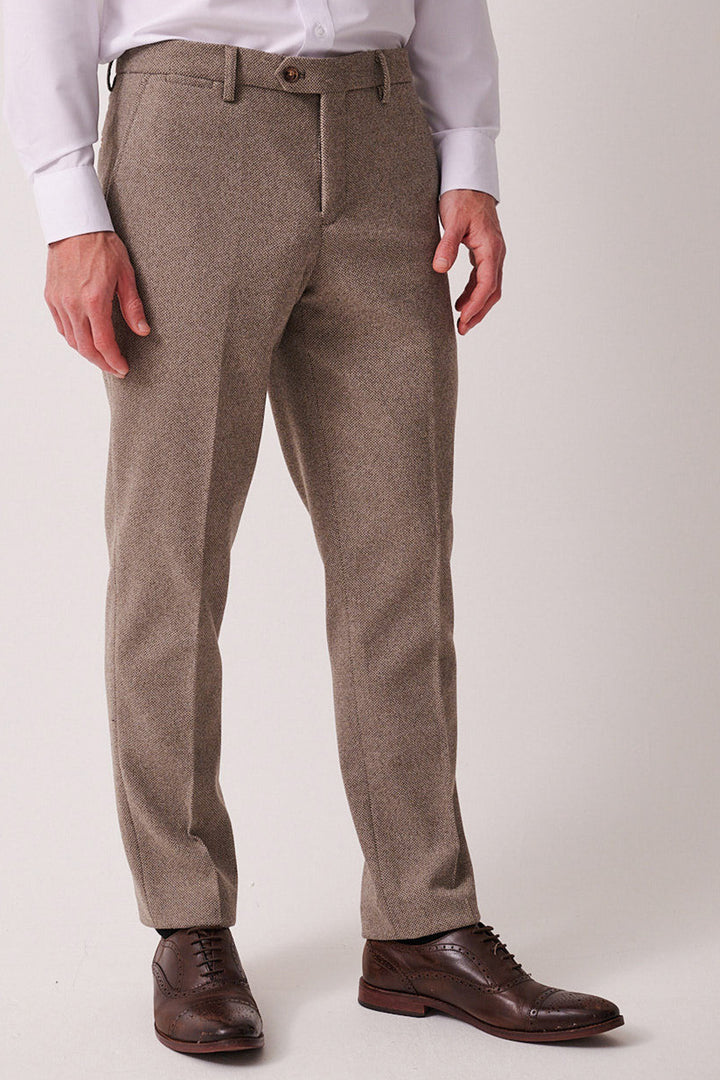 A man stands against a plain background, showing only his lower torso and legs, wearing the marcdarcy HAYDEN - Tan Crossweave Three Piece Suit.