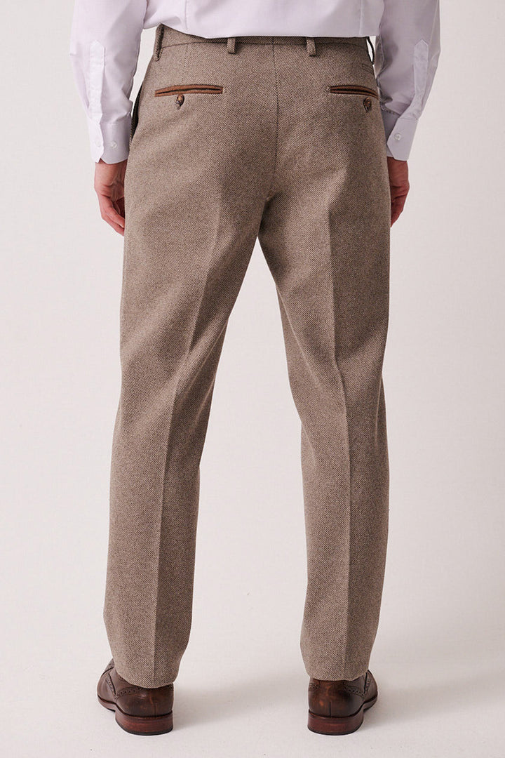 A man, seen from behind, wears the marcdarcy HAYDEN - Tan Crossweave Three Piece Suit with a white dress shirt, brown shoes, and a brown belt. The trousers feature two buttoned back pockets with brown trim.