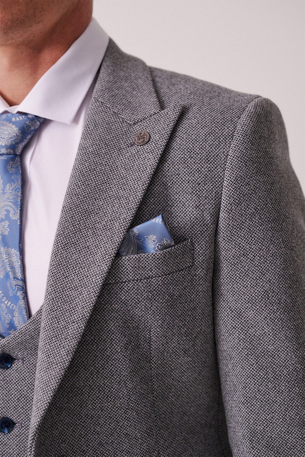 A close-up of a person wearing the marcdarcy HAYDEN Silver Blue Crossweave Blazer, paired with a white dress shirt and blue patterned tie, highlights the upper torso and classic tailored style.