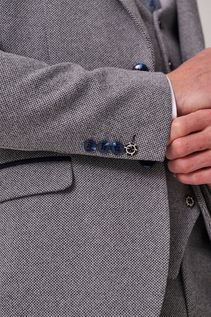 Close-up of a person wearing the marcdarcy HAYDEN - Silver Blue Crossweave Three Piece Suit, featuring dark blue buttons, a visible white shirt cuff, and a hand resting near the waist.