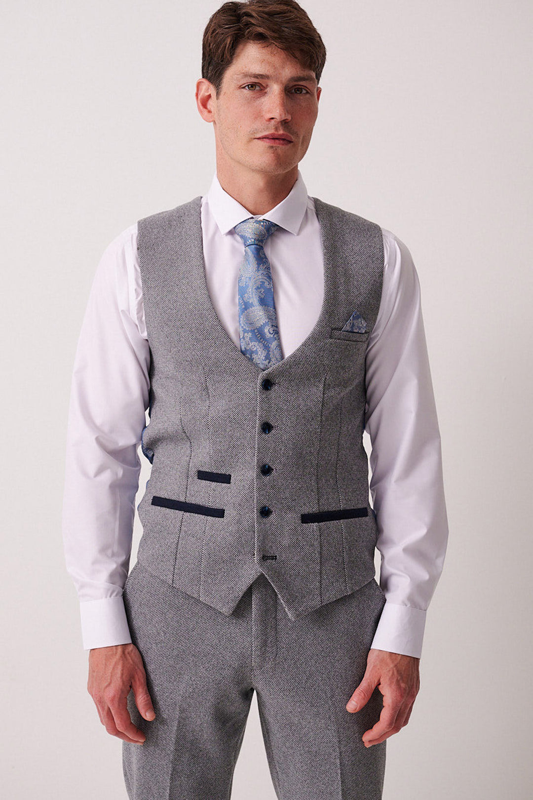 A man in a light grey Marc Darcy three-piece suit with a white shirt, blue patterned tie, and the HAYDEN Silver Blue Crossweave Waistcoat stands against a plain background.