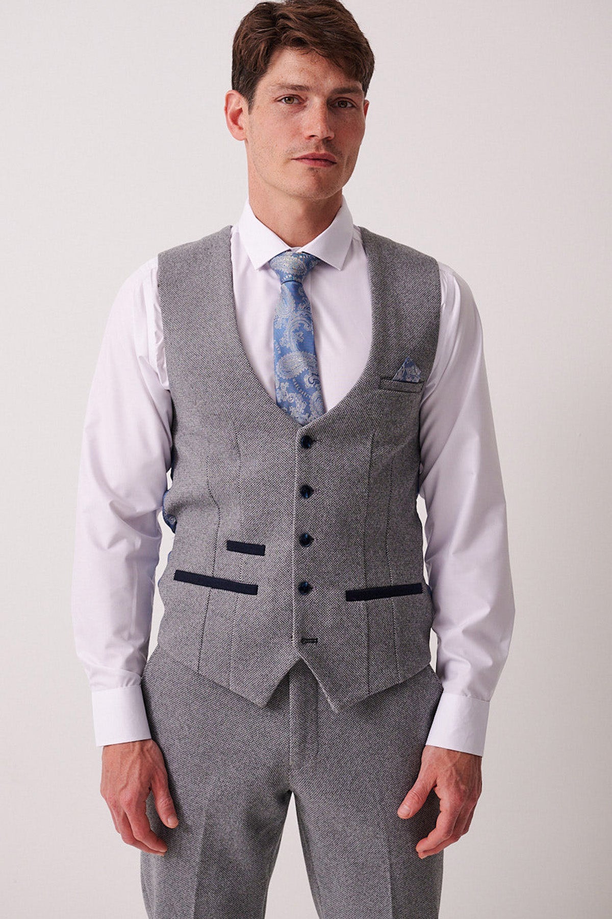 A man in a light grey Marc Darcy three-piece suit with a white shirt, blue patterned tie, and the HAYDEN Silver Blue Crossweave Waistcoat stands against a plain background.