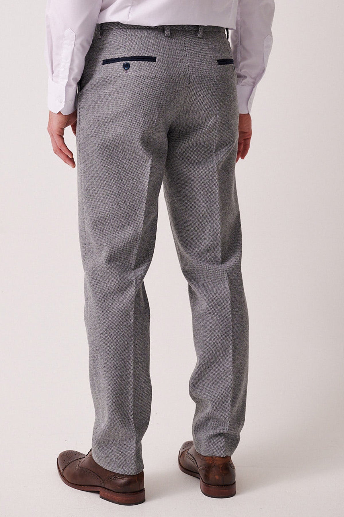 Man in marcdarcy HAYDEN Silver Blue Crossweave Trousers paired with a white shirt and brown dress shoes. Close-up on the back of the legs and shoes highlights a smart casual style.