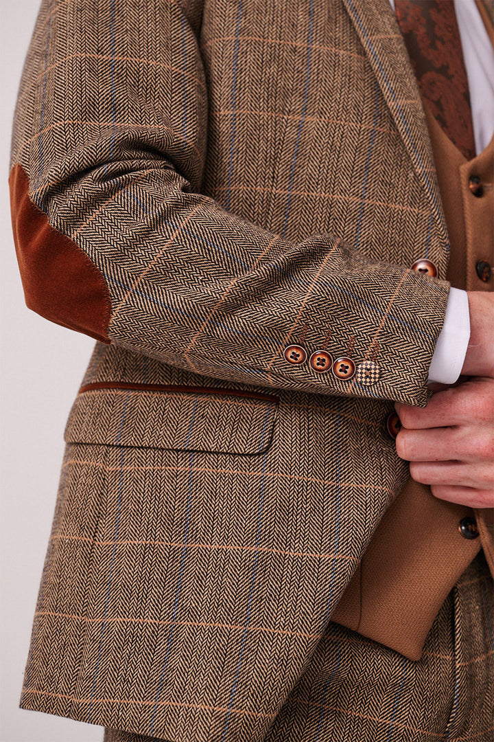 A close-up of a person wearing the marcdarcy DX7 Tan Tweed Check Suit with Kelvin Oak Waistcoat. Brown plaid tweed, elbow patches, and brown buttons pair perfectly for a country wedding. Shirt cuff peeks from the slim sleeve.