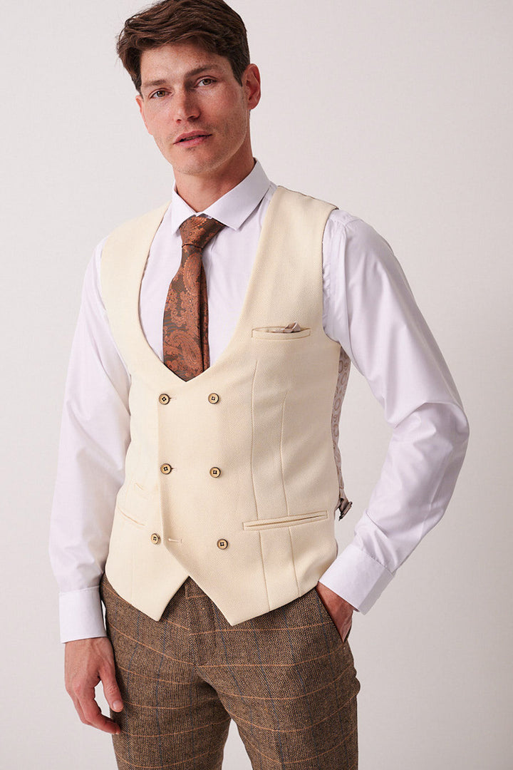 A man in the marcdarcy DX7 Tan Tweed Check Suit with a Kelvin Cream Waistcoat, white shirt, and brown patterned tie creates a vintage-inspired look, ideal for a stylish country wedding.