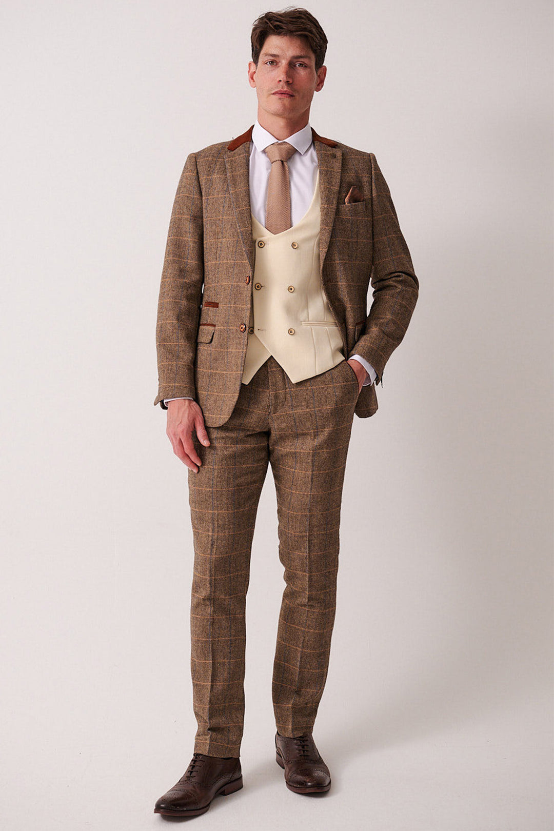 A man wears the marcdarcy DX7 Tan Tweed Check Suit with Kelvin Cream Waistcoat, styled with a white shirt, tan tie, and pocket square for a vintage-inspired look.