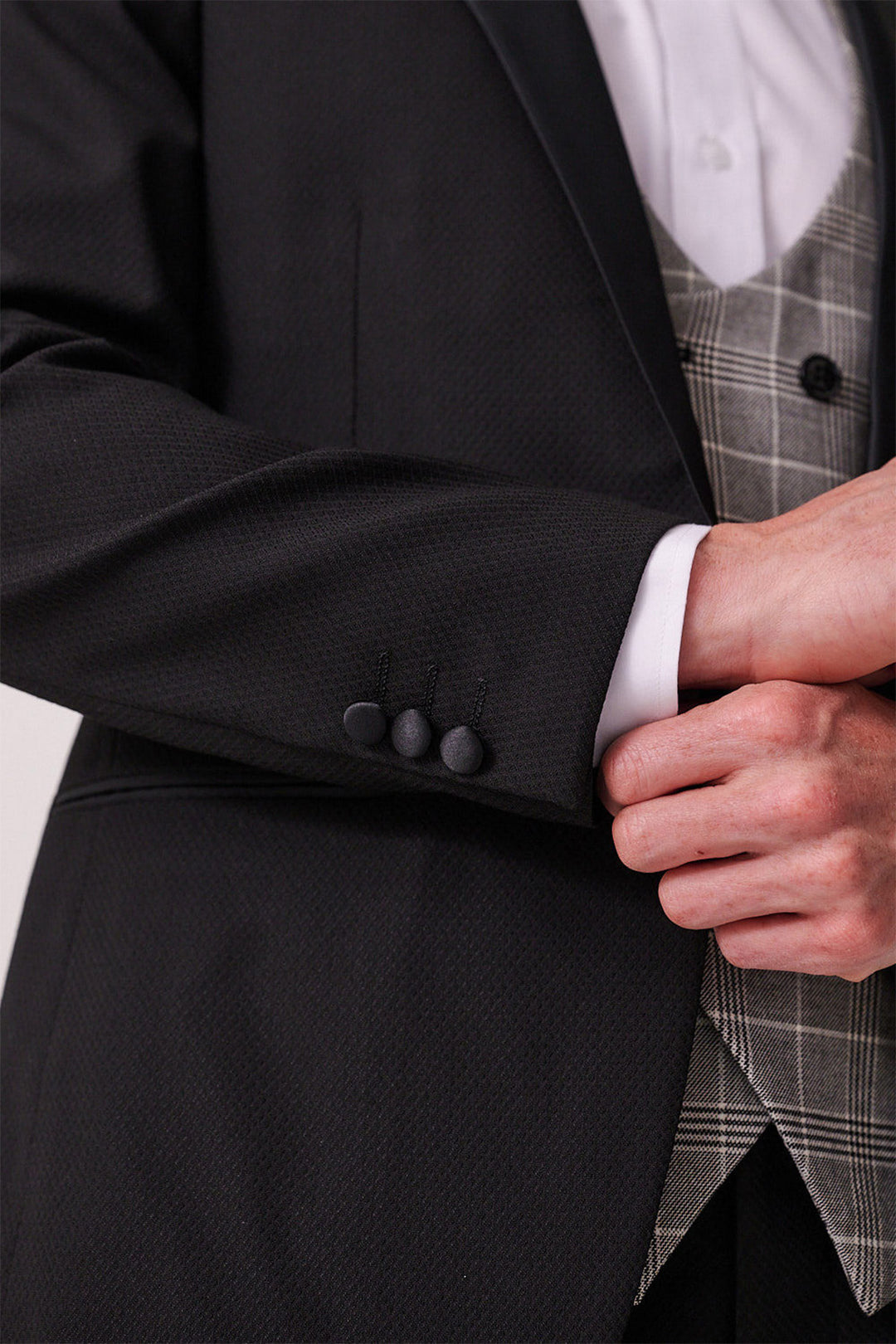 Close up of a person wearing the marcdarcy DALTON Black Tux Lapel Suit with Ross Waistcoat: features a black textured slim-fit blazer, white shirt, and gray plaid waistcoat—perfect for black tie events.