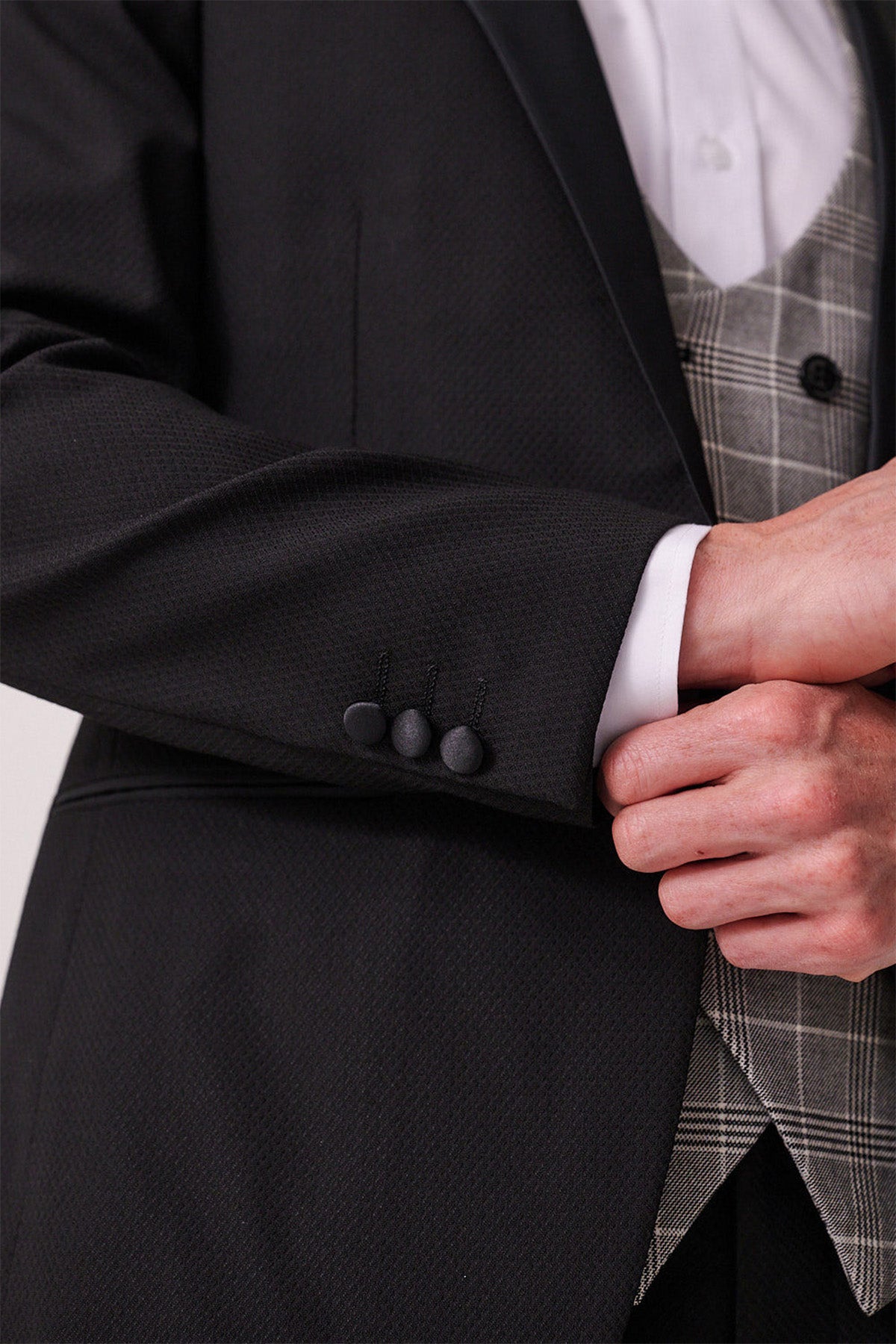 Close up of a person wearing the marcdarcy DALTON Black Tux Lapel Suit with Ross Waistcoat: features a black textured slim-fit blazer, white shirt, and gray plaid waistcoat—perfect for black tie events.