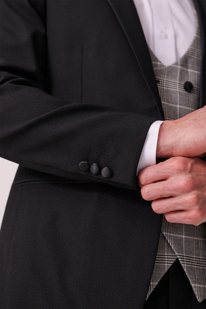 Close up of a person wearing the marcdarcy DALTON Black Tux Lapel Suit with Ross Waistcoat: features a black textured slim-fit blazer, white shirt, and gray plaid waistcoat—perfect for black tie events.