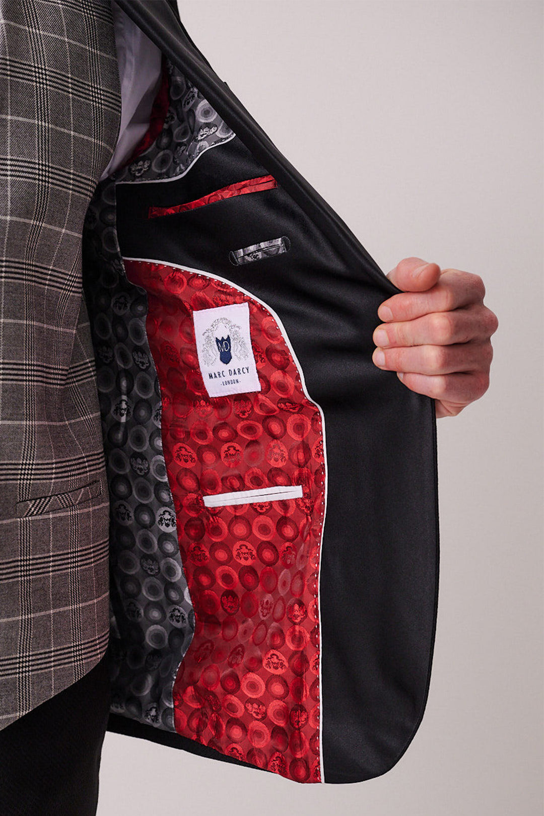 A person holds open a DALTON - Black Tux Lapel Suit With Ross Waistcoat by marcdarcy, revealing a vibrant red and black patterned lining with pockets and a visible marcdarcy label inside.