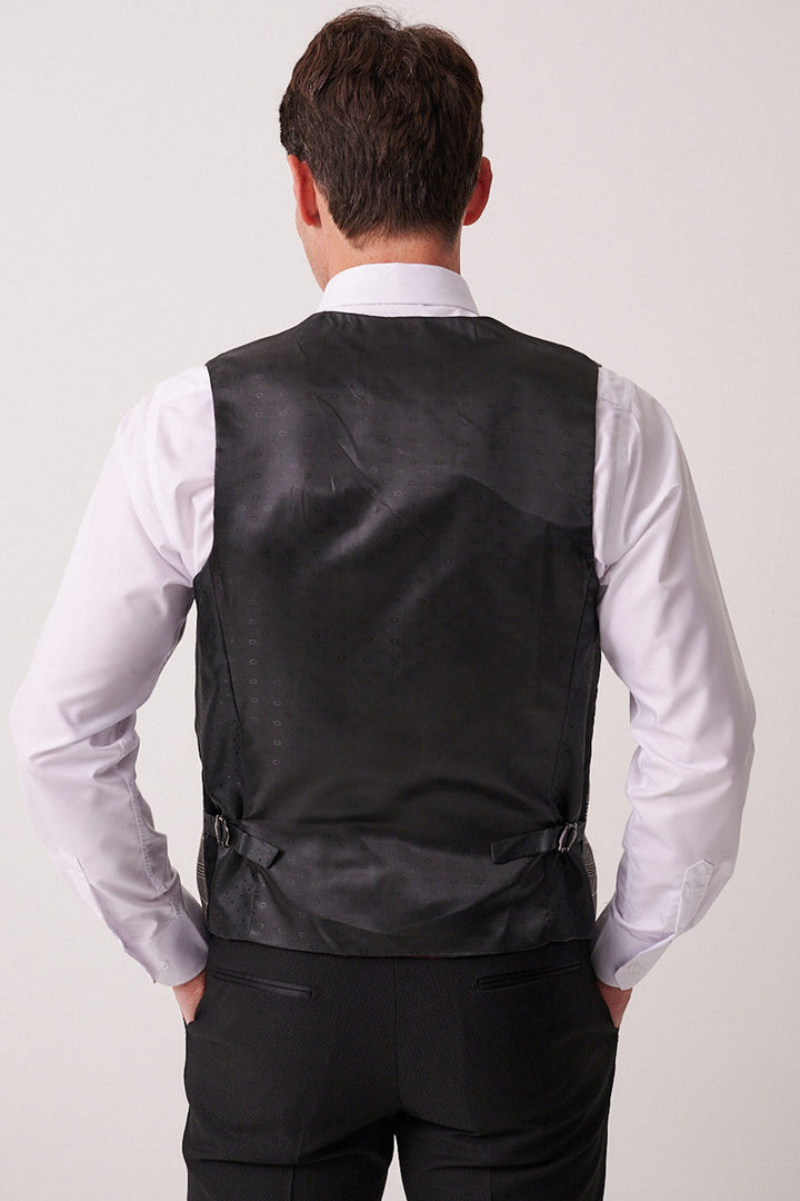 A man wearing the marcdarcy DALTON Black Tux Lapel Suit with Ross Waistcoat stands with his back to the camera, hands on his hips.