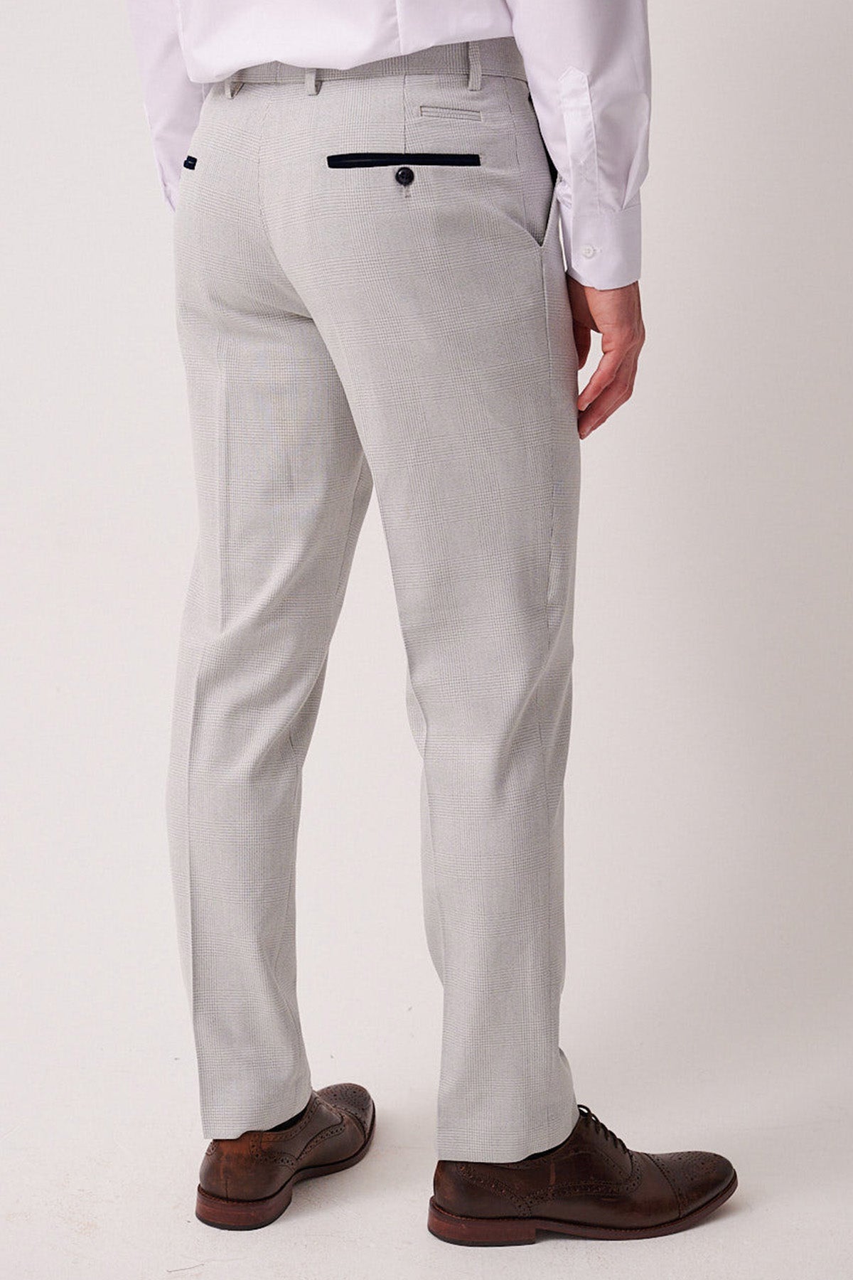 A man shown from the back wears Marc Darcy's BROMLEY Stone Check Suit trousers with black buttoned back pockets, a tailored fit, white shirt, and brown shoes. Part of the set with a Kelvin Navy Waistcoat.