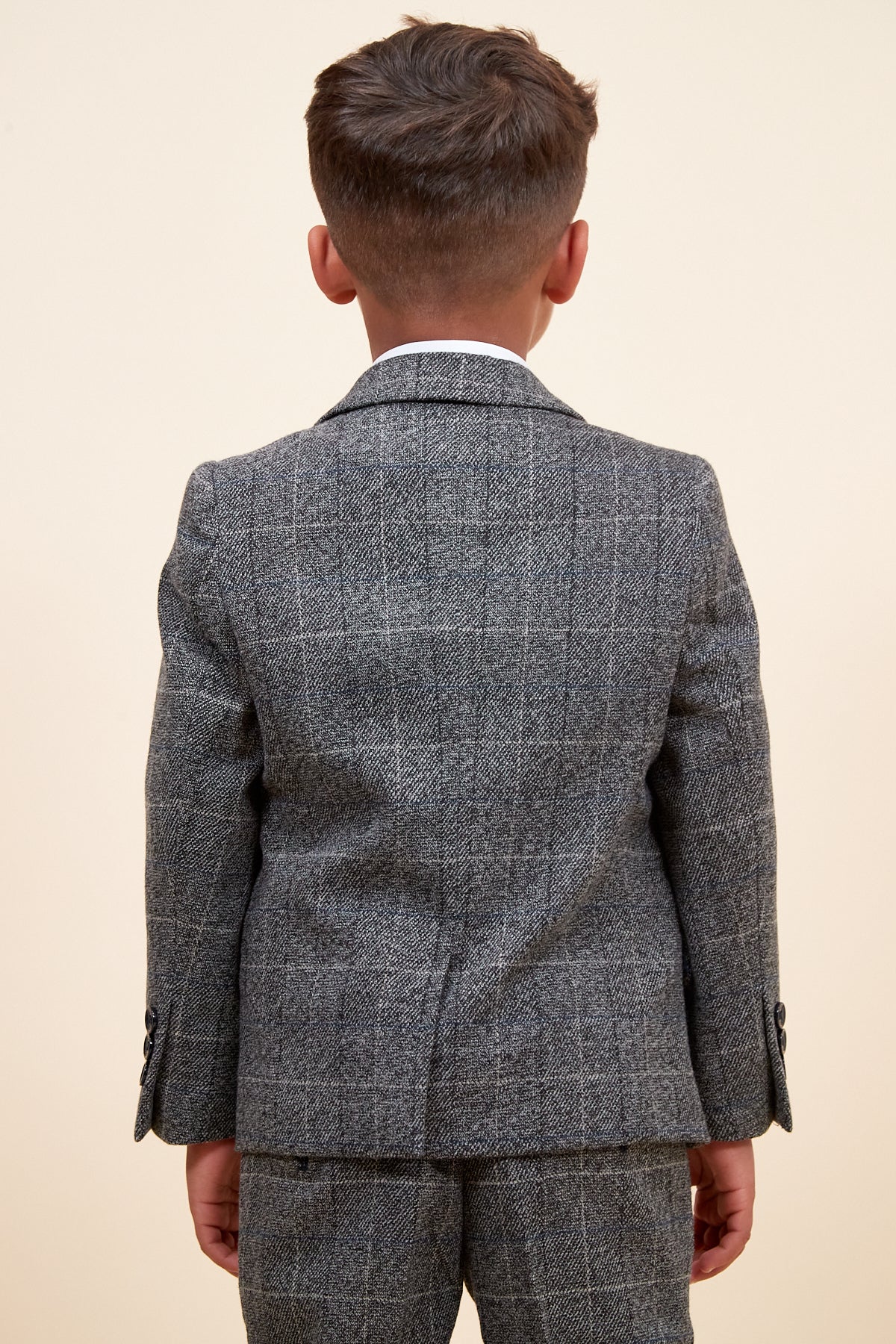 Rear view of a young boy wearing the marcdarcy SCOTT Children's Grey Check Three Piece Suit, designed with an adjustable waistband for comfort.