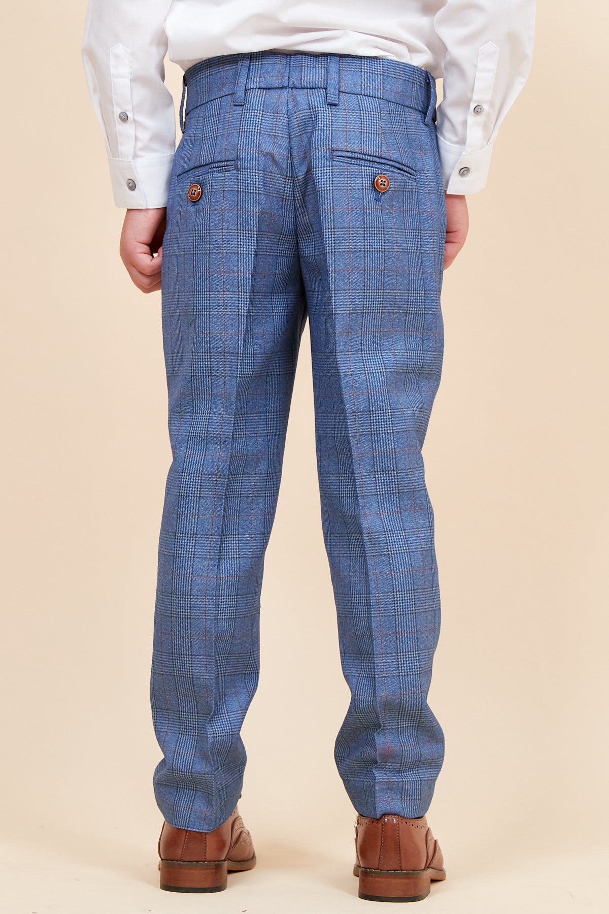 Back view of a boy in the marcdarcy GEORGE Children's Light Blue Check Three Piece Suit, featuring blue check pants, a white dress shirt, and brown dress shoes.