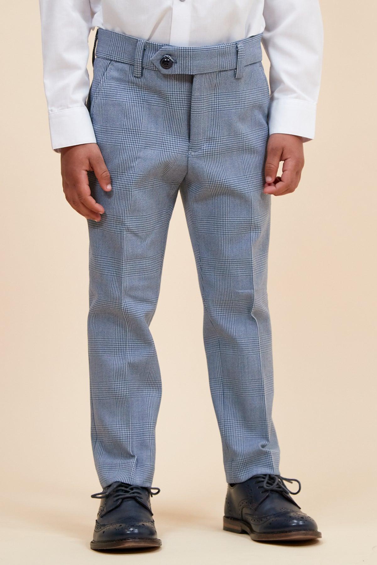 A child wearing the Marc Darcy BROMLEY children's sky blue check print three piece suit stands on a plain beige background.