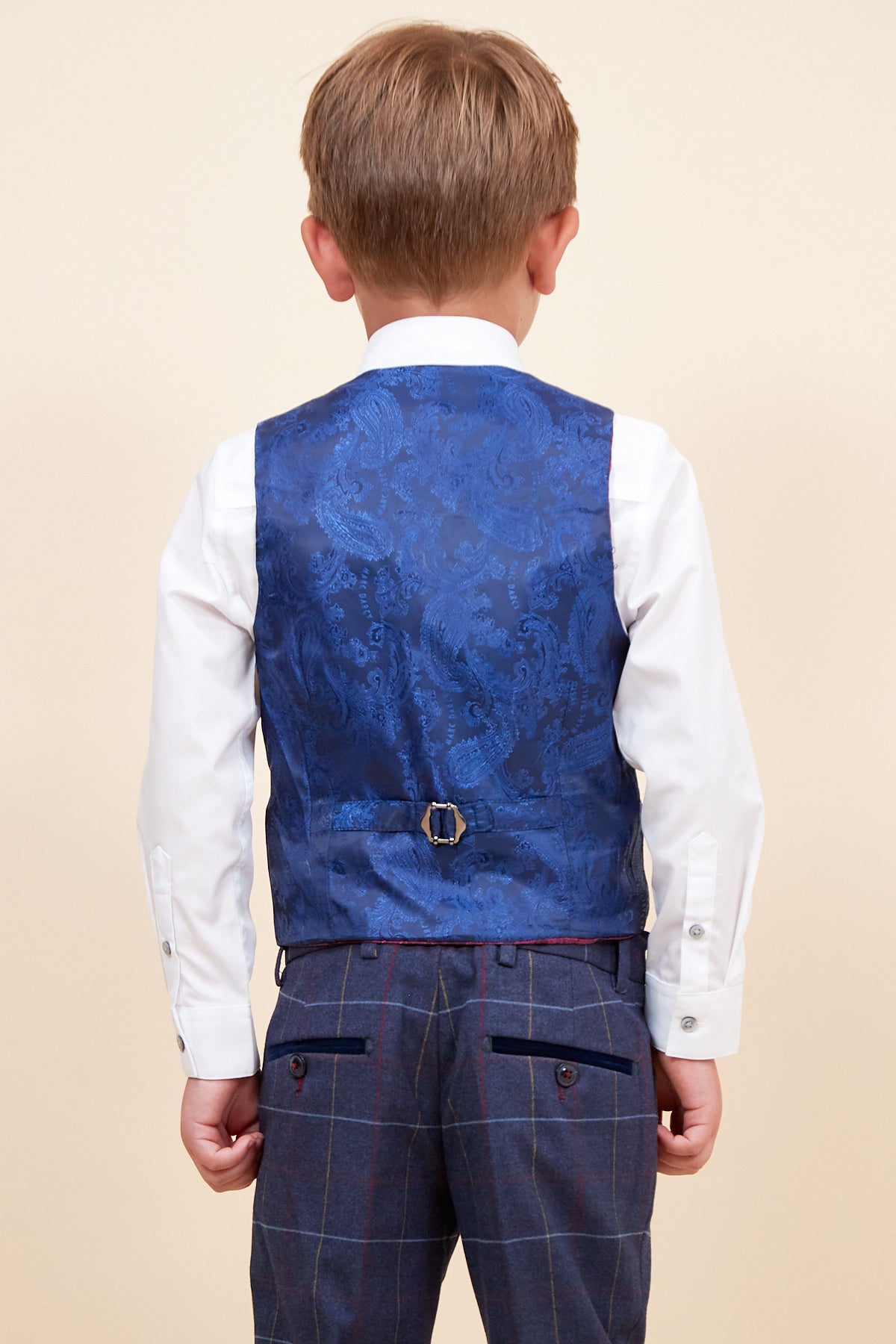 Back view of a boy wearing the marcdarcy DRAKE Children's Navy Check Three Piece Suit, featuring a white shirt, blue paisley vest, and plaid adjustable trousers—ideal as a stylish pageboy or children's suit for special occasions.