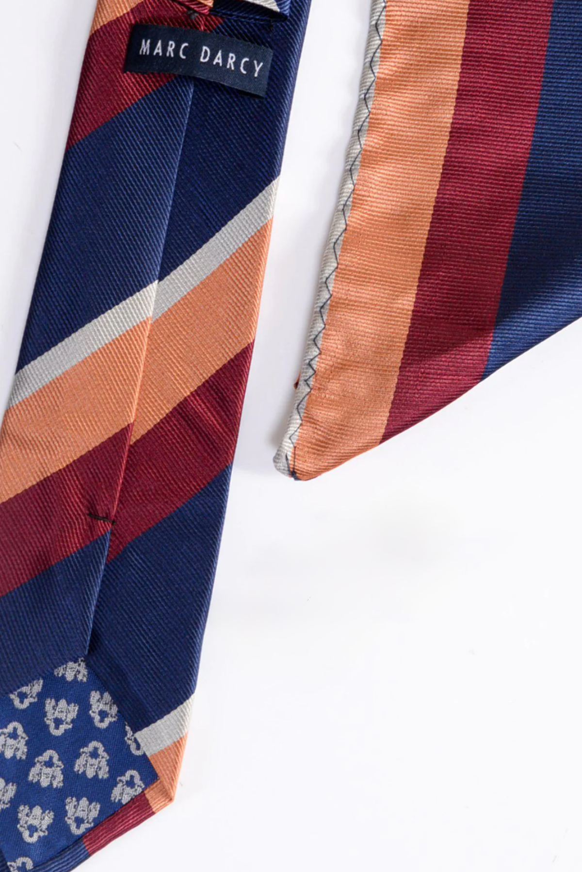 The BRUNO Multicolour Stripe Print Tie and Pocket Square Set by Marc Darcy features dark blue with diagonal navy, burgundy, tan, and gray stripes—a sharp pick for any striped accessory collection.
