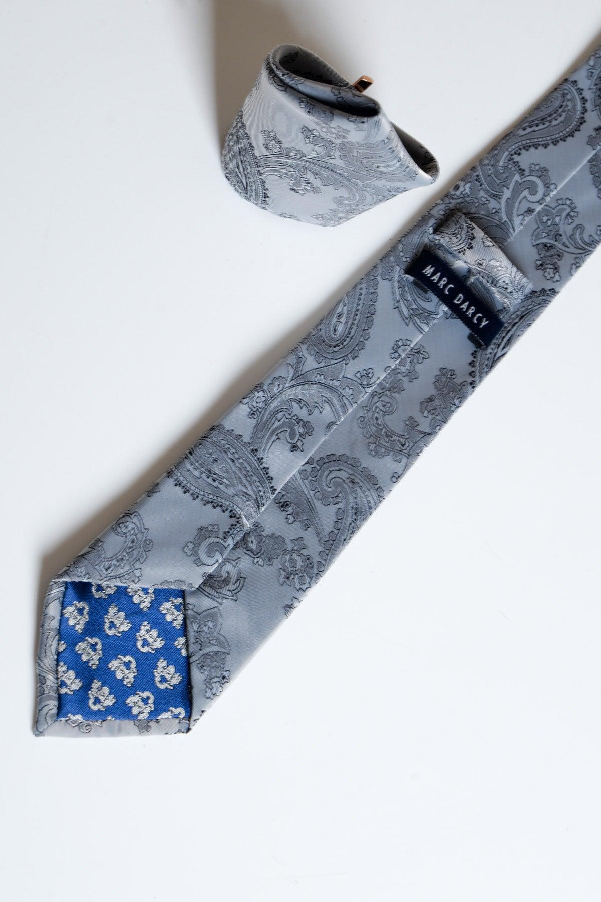 The MD PAISLEY - Grey Paisley Tie and Pocket Square Set by Accessory features a paisley-patterned tie with a blue floral reverse and matching pocket square, displayed on white—ideal modern accessories for formalwear.