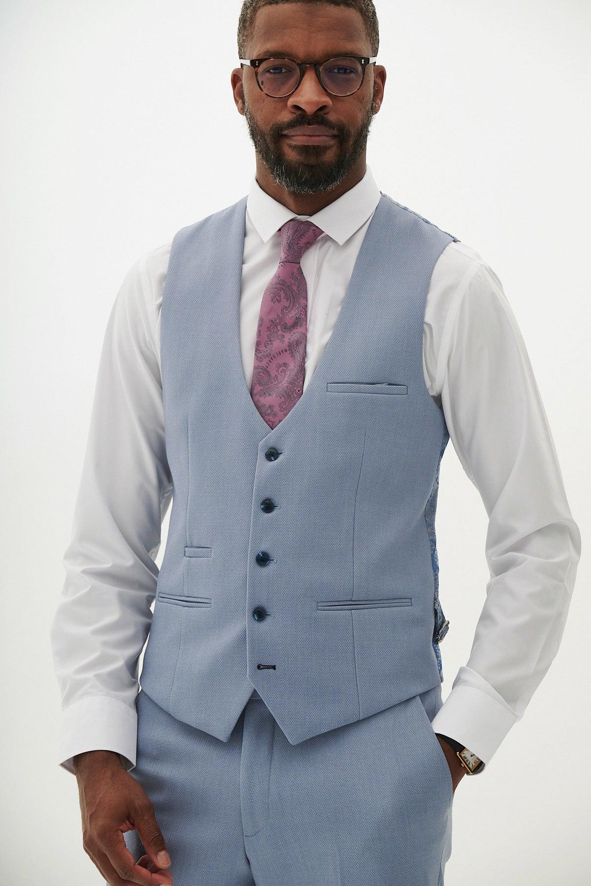A Black man, bearded and wearing glasses, models the marcdarcy HM5 Sky Blue Single Breasted Waistcoat paired with a white shirt and pink paisley tie.