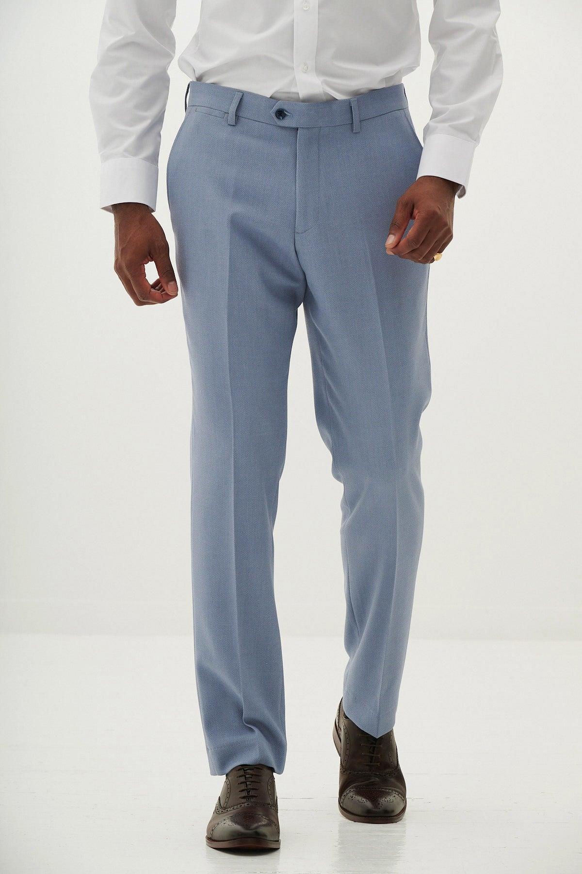 A man wears the Marc Darcy HM5 - Sky Blue Three Piece Suit, styled with a white shirt and brown dress shoes, standing with his hands at his sides.