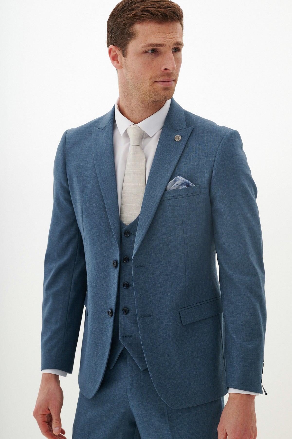 A man wearing the Marc Darcy FINLEY teal blue three-piece suit, paired with a white shirt and beige tie, poses against a white background.