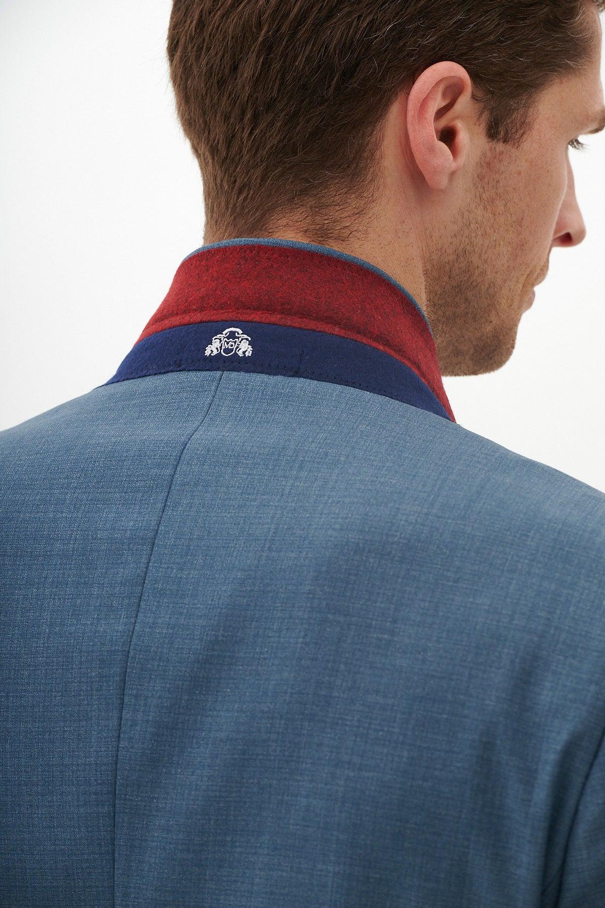 A man seen from behind wears the Marc Darcy FINLEY - Teal Blue Tailored Blazer with a popped collar, revealing red and navy interior lining featuring a central white embroidered design.