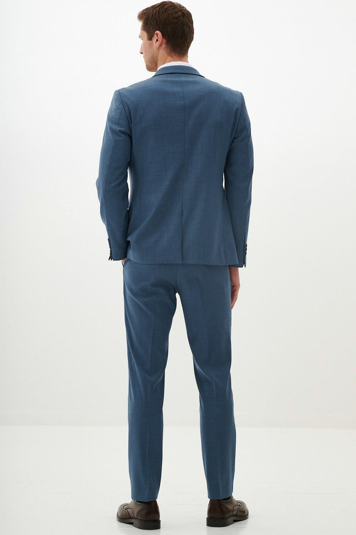A man in the Marc Darcy FINLEY - Teal Blue Two Piece Suit and brown dress shoes stands facing away, looking left against a white background—an ideal choice for summer weddings.