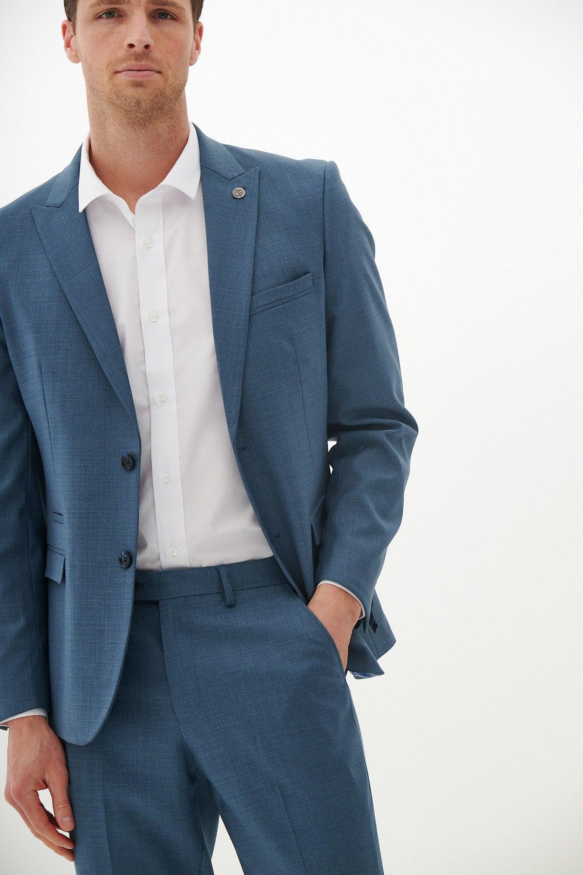 A man wearing the FINLEY - Teal Blue Tailored Blazer by Marc Darcy, styled with a white shirt and one hand in his pocket.