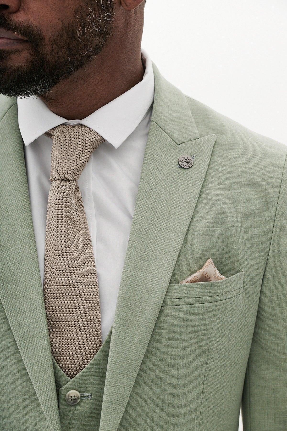 A man wears the Marc Darcy FINLEY Moss Green Three Piece Suit—perfect for summer weddings—paired with a beige textured tie, white dress shirt, and beige pocket square. Only his lower face and upper body are visible.