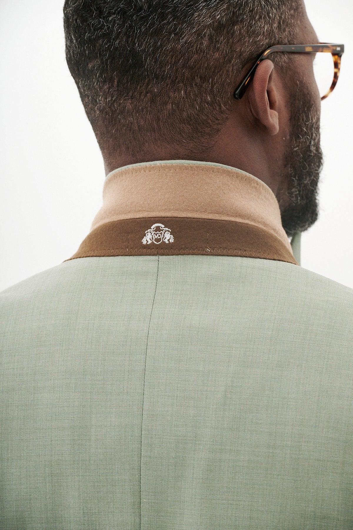A man with short hair and glasses is seen from behind wearing the Marc Darcy FINLEY - Moss Green Tailored Blazer, featuring a slim fit, tan collar, and a small white embroidered logo, perfect for spring and summer style.
