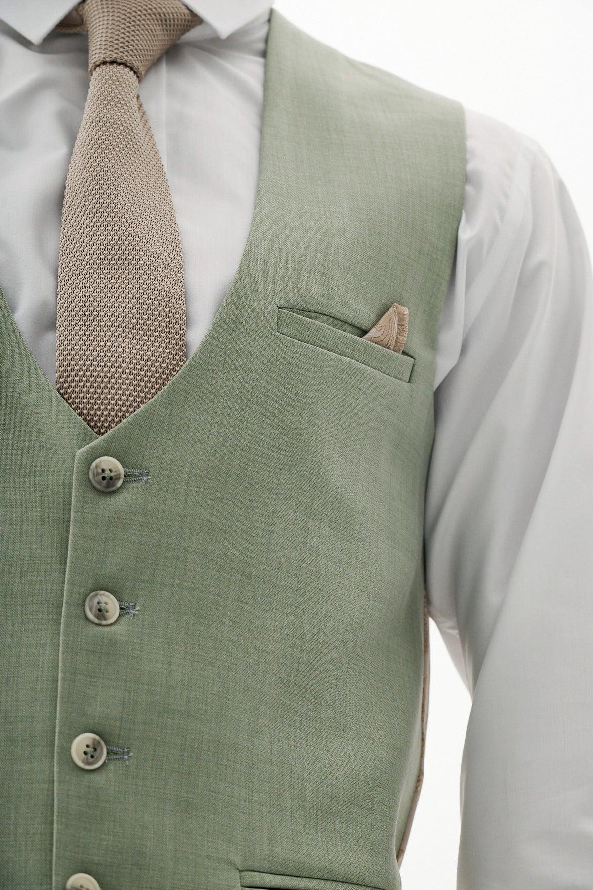 A man wears the Marc Darcy FINLEY - Moss Green Three Piece Suit with a white shirt, textured tan tie, and tan pocket square—an ideal look for a summer wedding.