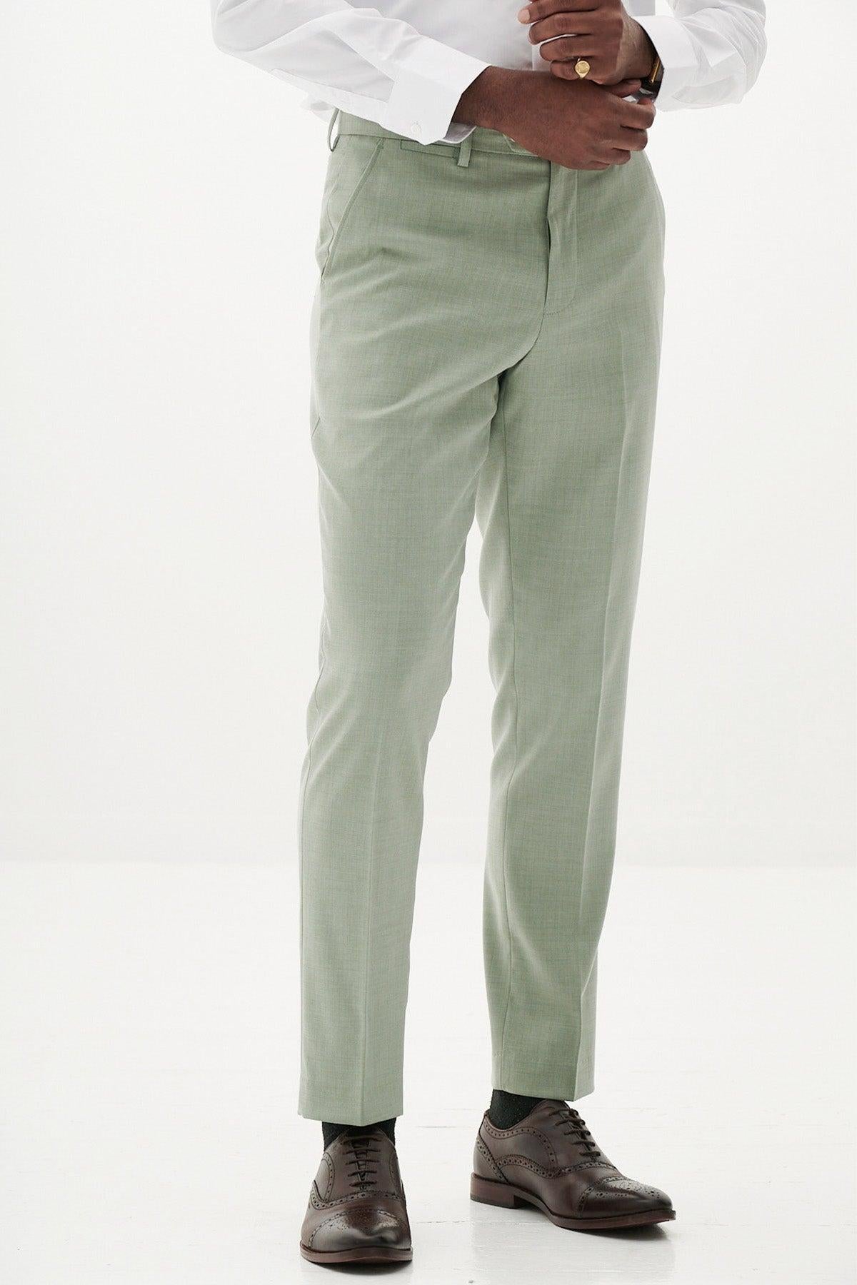 A person wears Marc Darcy’s FINLEY Moss Green Tailored Trousers, paired with a white dress shirt and brown oxford shoes, standing against a plain white background. Only the body from shoulders down is visible.