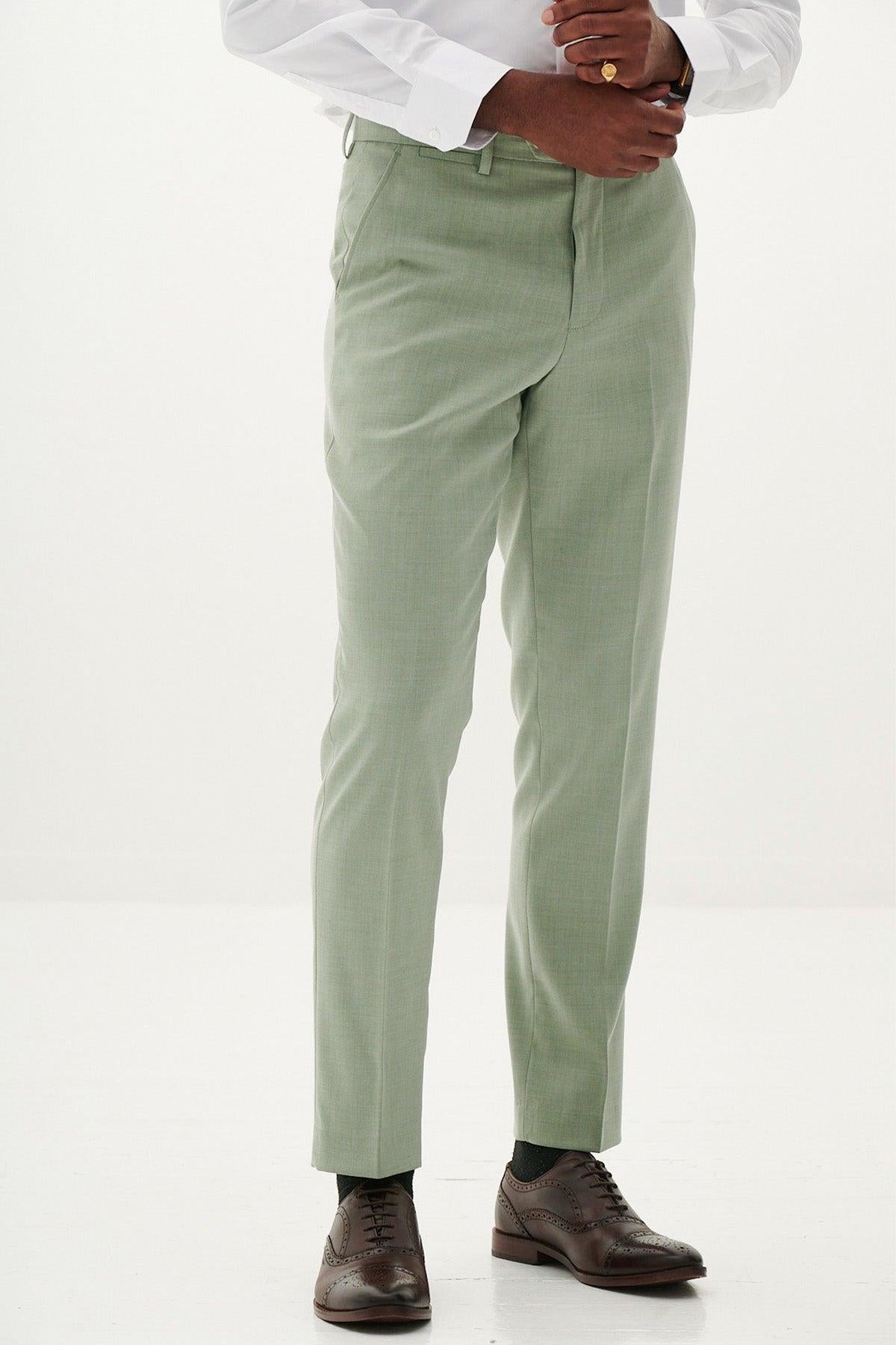 A person stands against a plain white background wearing the Marc Darcy FINLEY - Moss Green Two Piece Suit, paired with a white dress shirt, brown leather dress shoes, and a gold ring. The image is cropped at the shoulders—ideal for summer weddings.