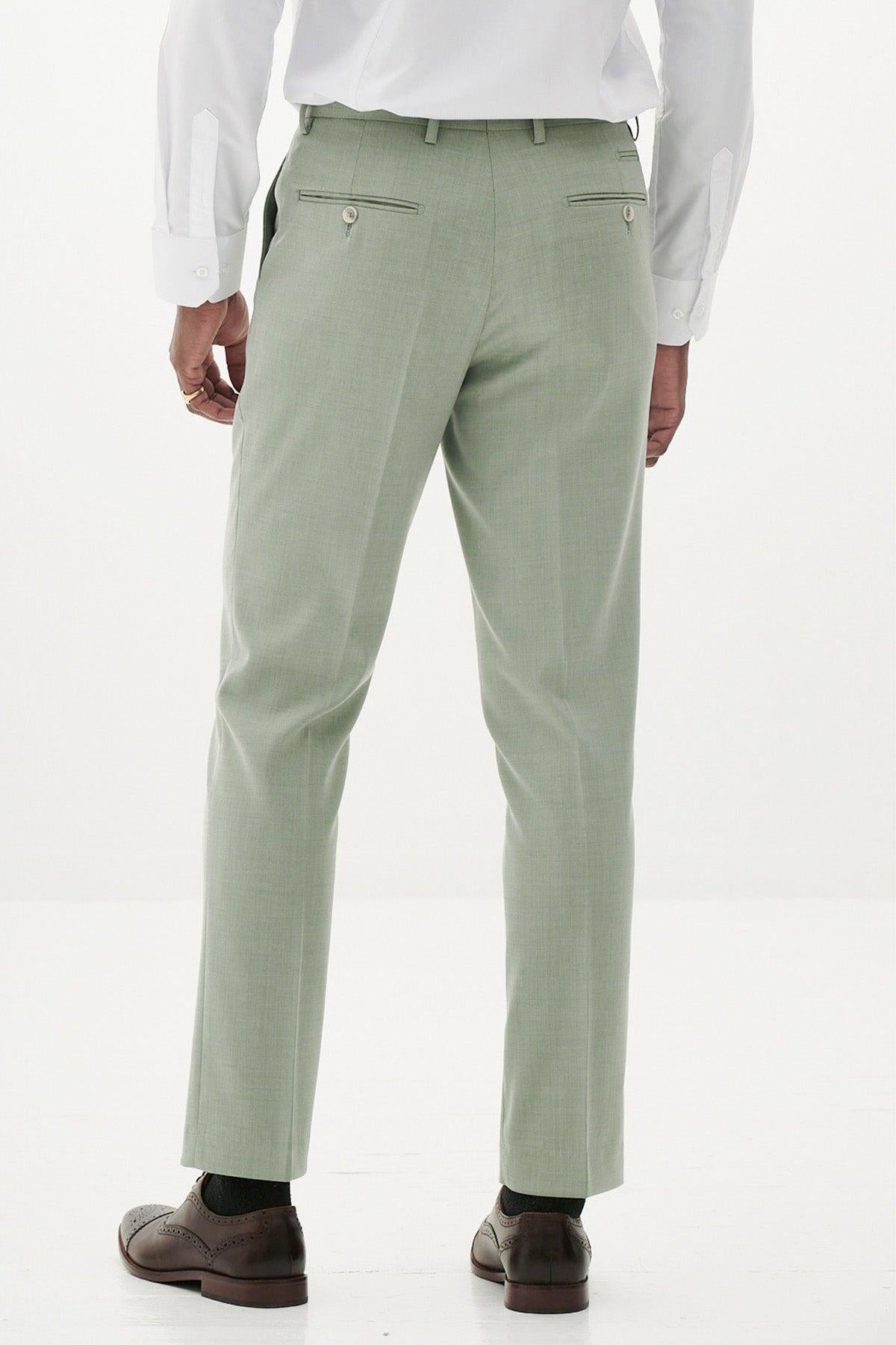 A man faces away, wearing Marc Darcy's FINLEY - Moss Green Tailored Trousers with a white dress shirt, black socks, and brown dress shoes against a plain white background.