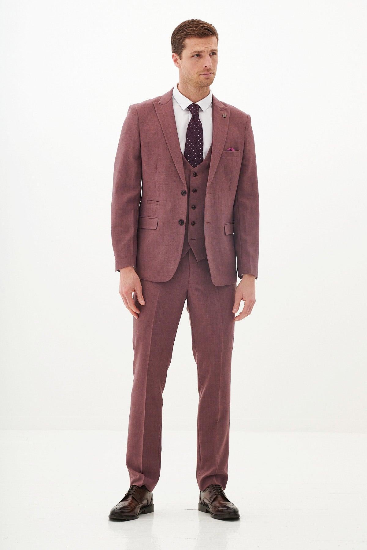 A man with short brown hair stands against a white background wearing the Marc Darcy MONTY Mauve Three Piece Suit, styled with a white shirt, dark patterned tie, and brown shoes—perfect for summer weddings. He looks slightly to his left.
