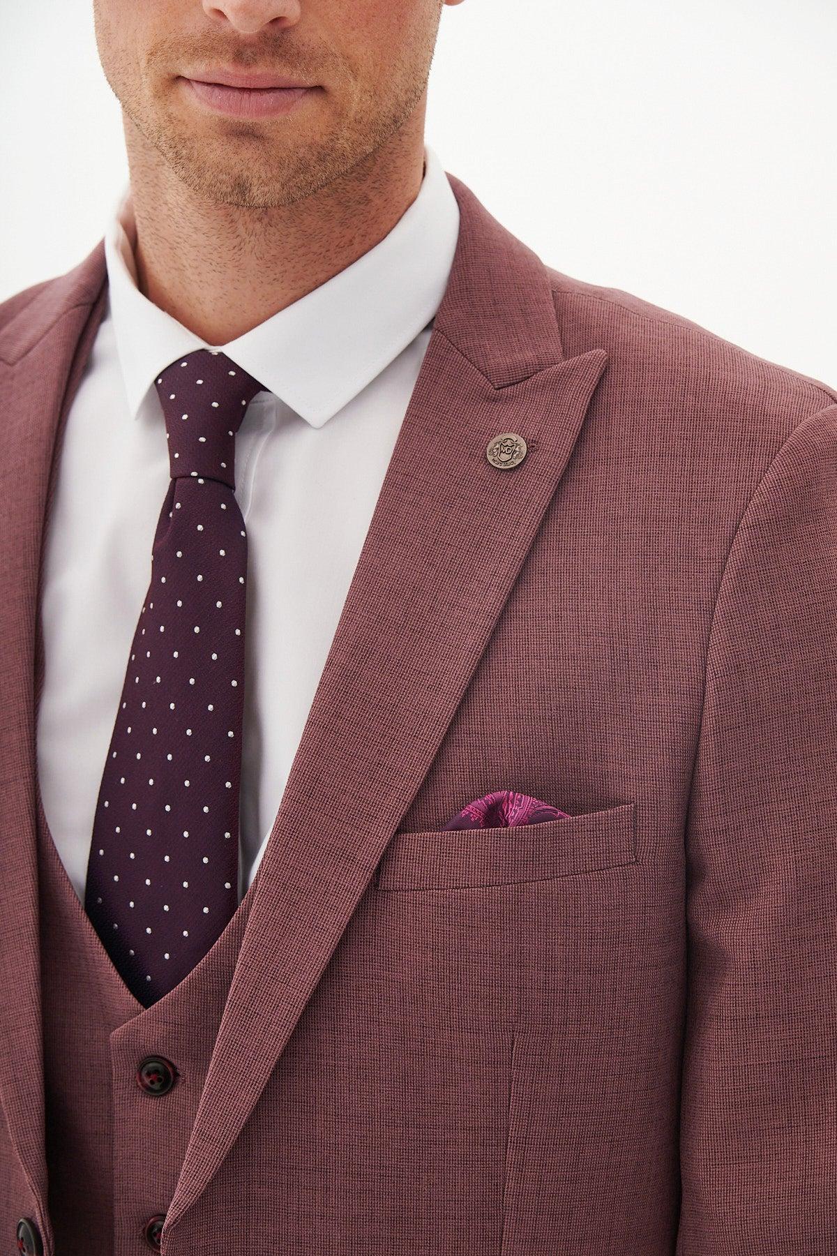 A man models the Marc Darcy MONTY Mauve Three Piece Suit with a white shirt, dark purple polka dot tie, pocket square, and lapel pin against a plain background—an ideal look for summer weddings.