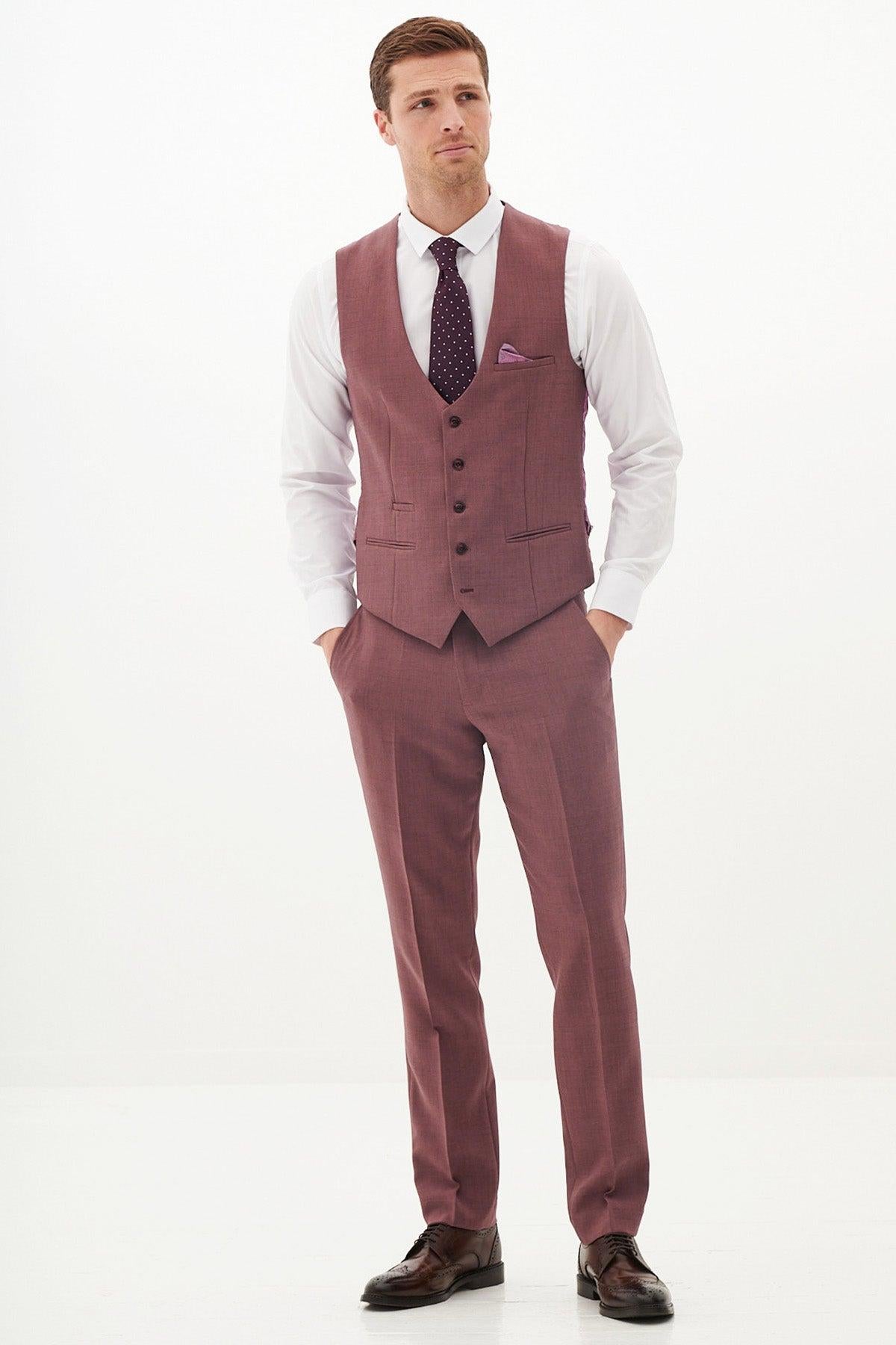 A man in the Marc Darcy MONTY Mauve Single Breasted Waistcoat stands with his hands in his pockets against a white background—perfect for a summer wedding look.