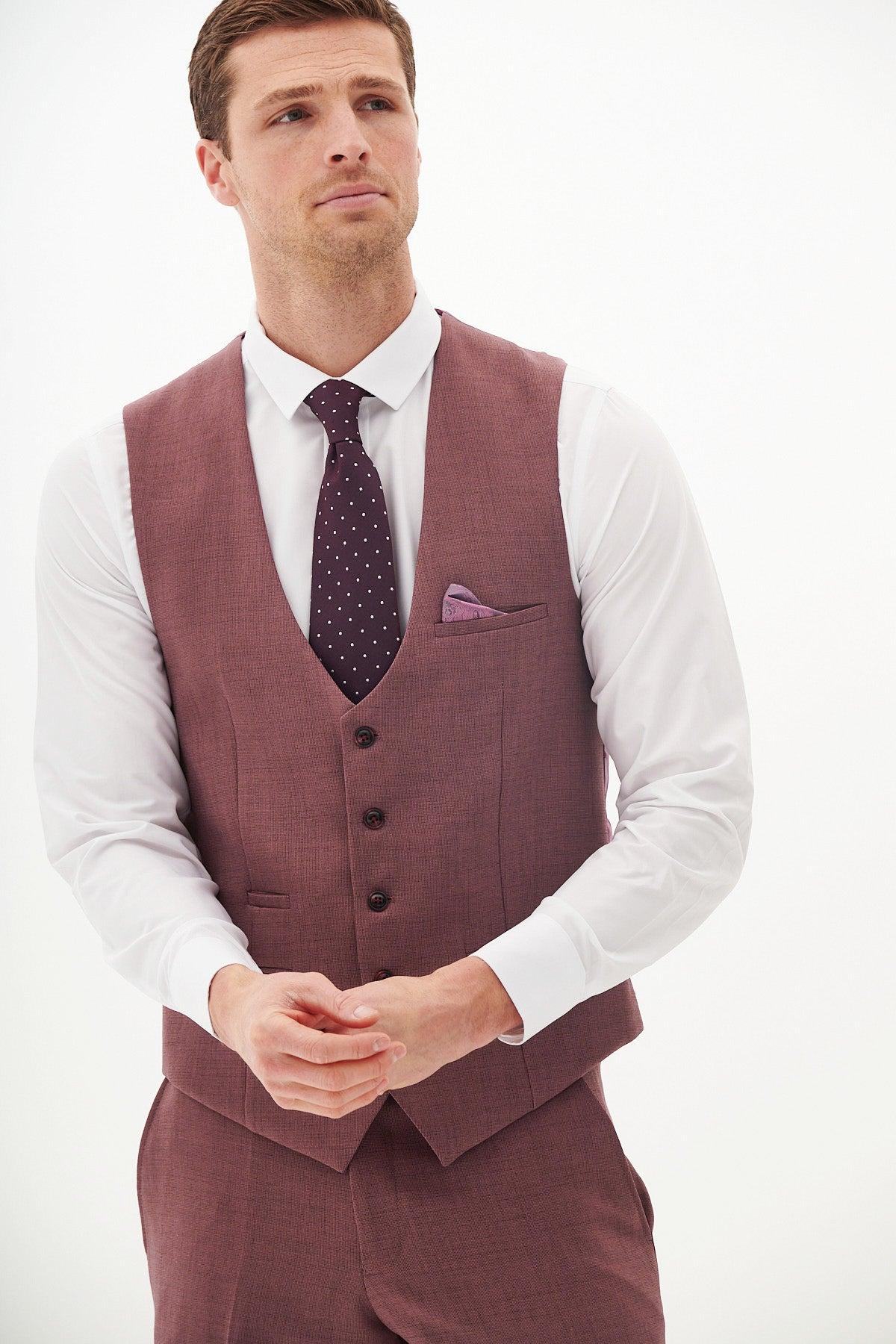 A man in the Marc Darcy MONTY mauve single-breasted waistcoat with a white shirt and dark purple polka dot tie stands against a white background, hands clasped and looking upward—perfect for a stylish summer wedding outfit.