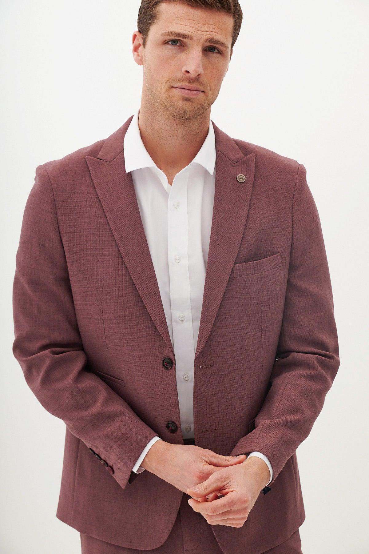 A man wears the Marc Darcy MONTY Mauve Tailored Blazer in a slim fit with peak lapels, paired with a white shirt. Hands clasped against a white background—modern sophistication in formalwear.