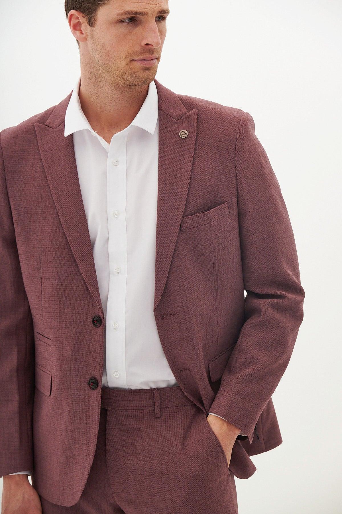 A man models the Marc Darcy MONTY - Mauve Two Piece Suit with a white dress shirt, standing against a plain white background and looking slightly right with one hand in his pocket.