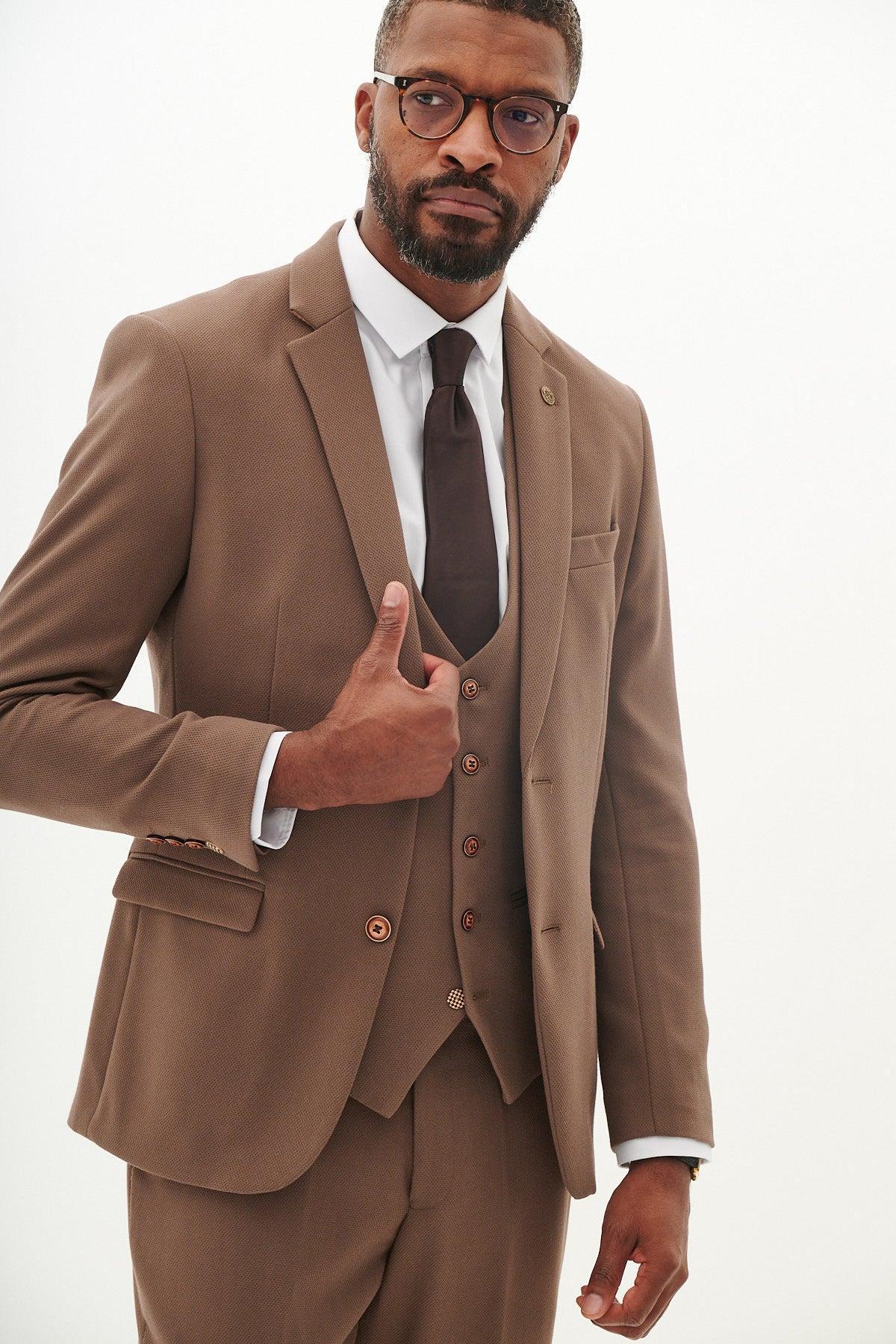 Man in the Marc Darcy HM5 Tan Tailored Suit from The West Bromwich Albion F.C. Collection, as seen on Michael Johnston, with a white shirt, dark tie, glasses, and giving a thumbs up.