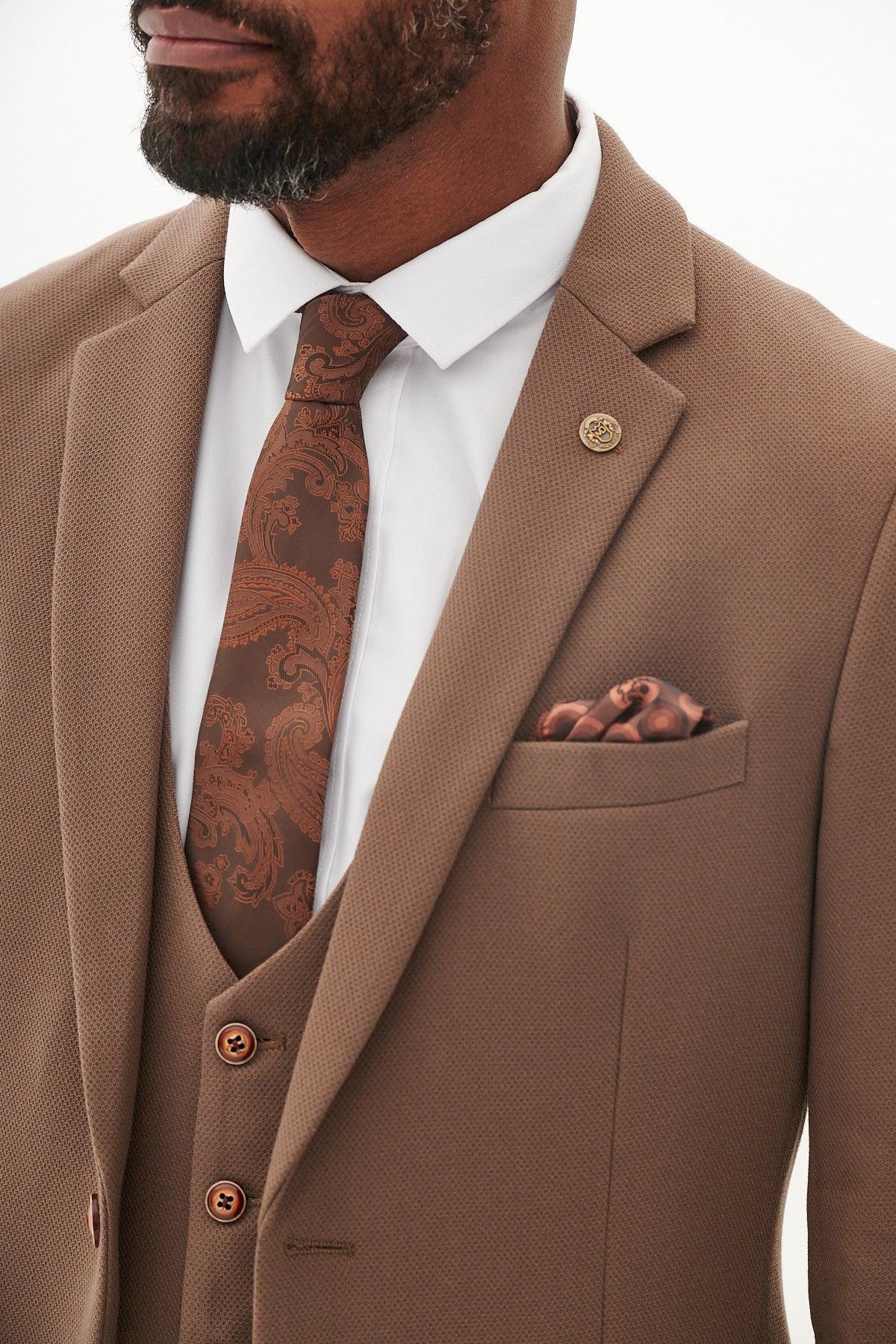 A man wears the Marc Darcy West Bromwich Albion F.C. Collection HM5 Tan Tailored Suit as seen on Michael Johnston, styled with a white shirt, brown paisley tie, and matching pocket square; only his upper torso and part of his face are visible.