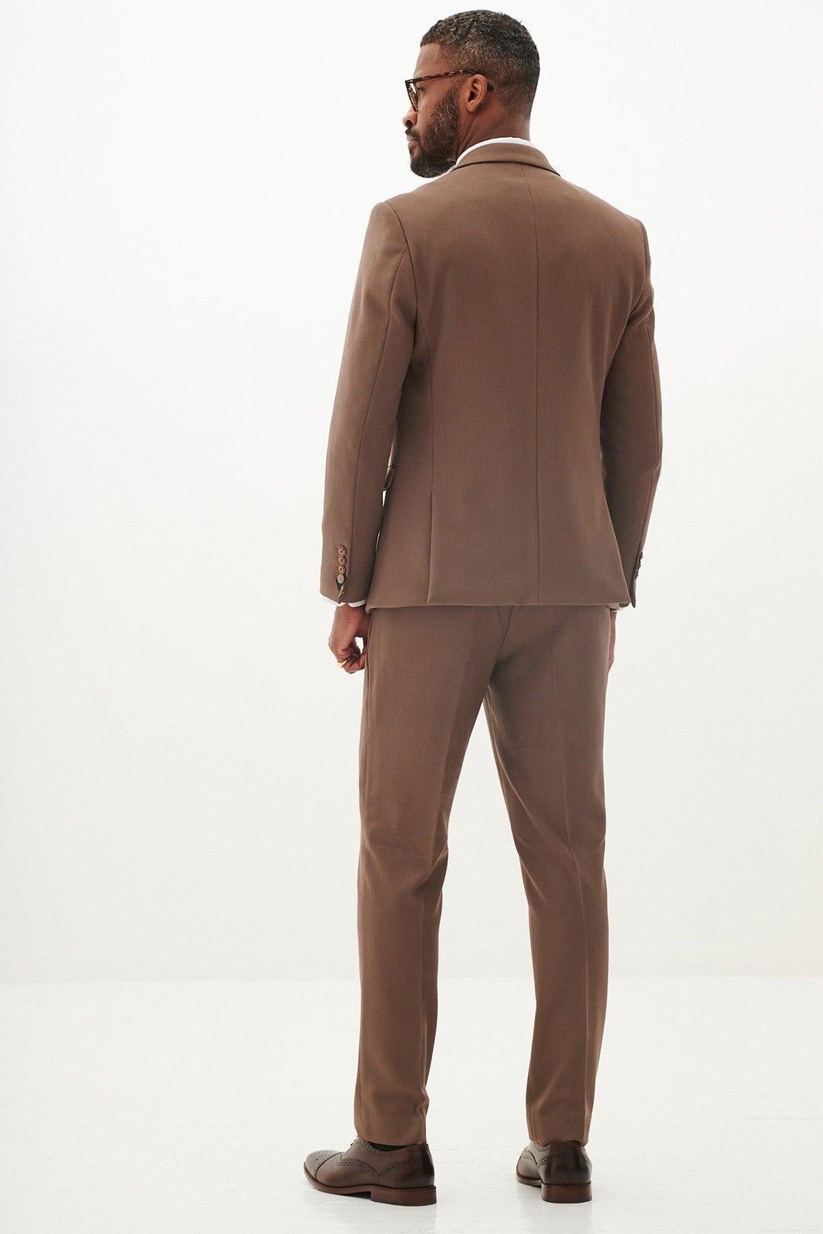A man, seen from the back, wears the Marc Darcy HM5 Tan Tailored Three Piece Suit with a white shirt, glasses, and brown dress shoes.