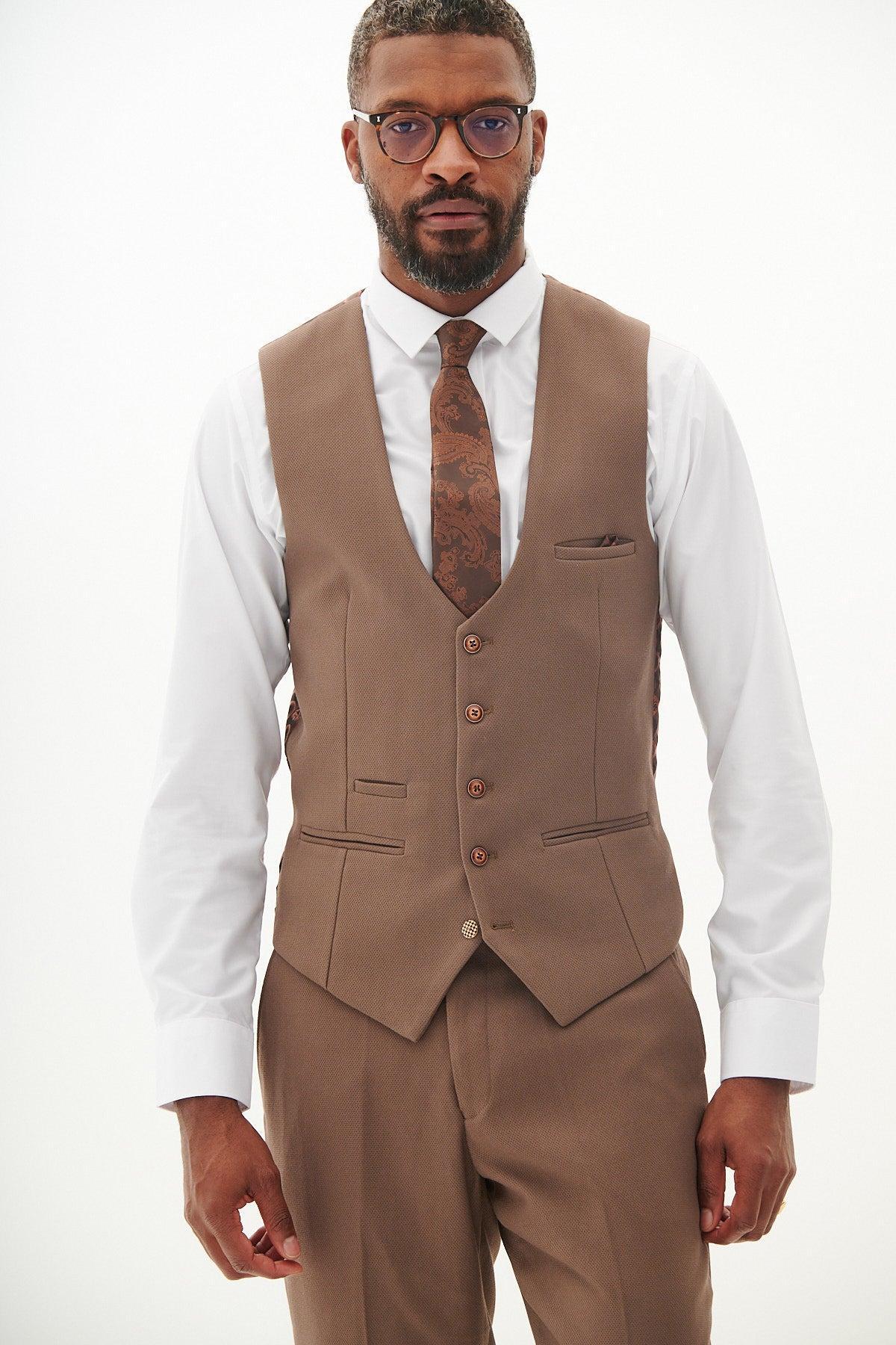 A man wearing glasses, a white dress shirt, a patterned tie, and the marcdarcy HM5 Tan Single Breasted Waistcoat with matching trousers stands against a plain light background, looking directly at the camera.