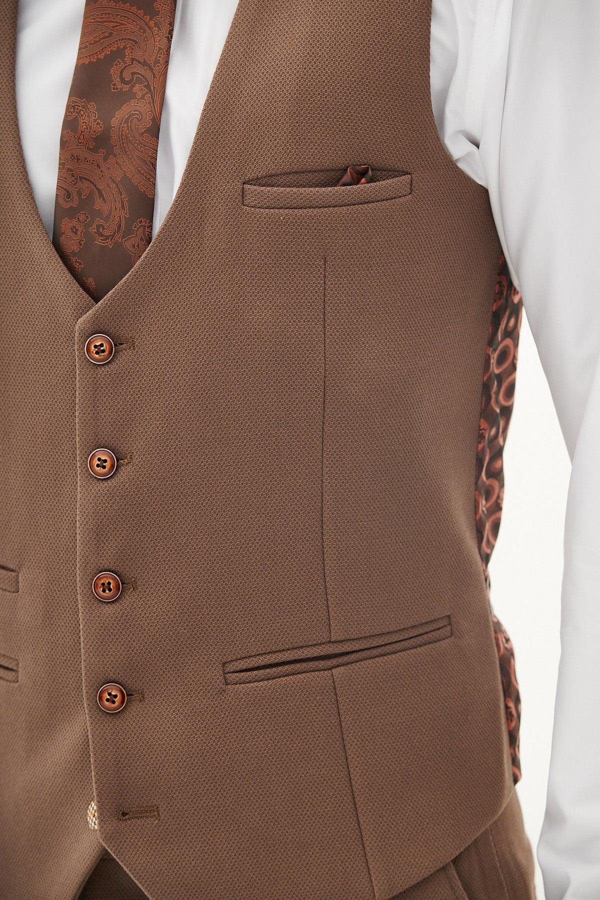 A close-up of the Marc Darcy HM5 Tan Tailored Suit Vest from The West Bromwich Albion F.C. Collection, as worn by Michael Johnston, featuring four buttons, a pocket square, and paired with a paisley tie and white shirt.