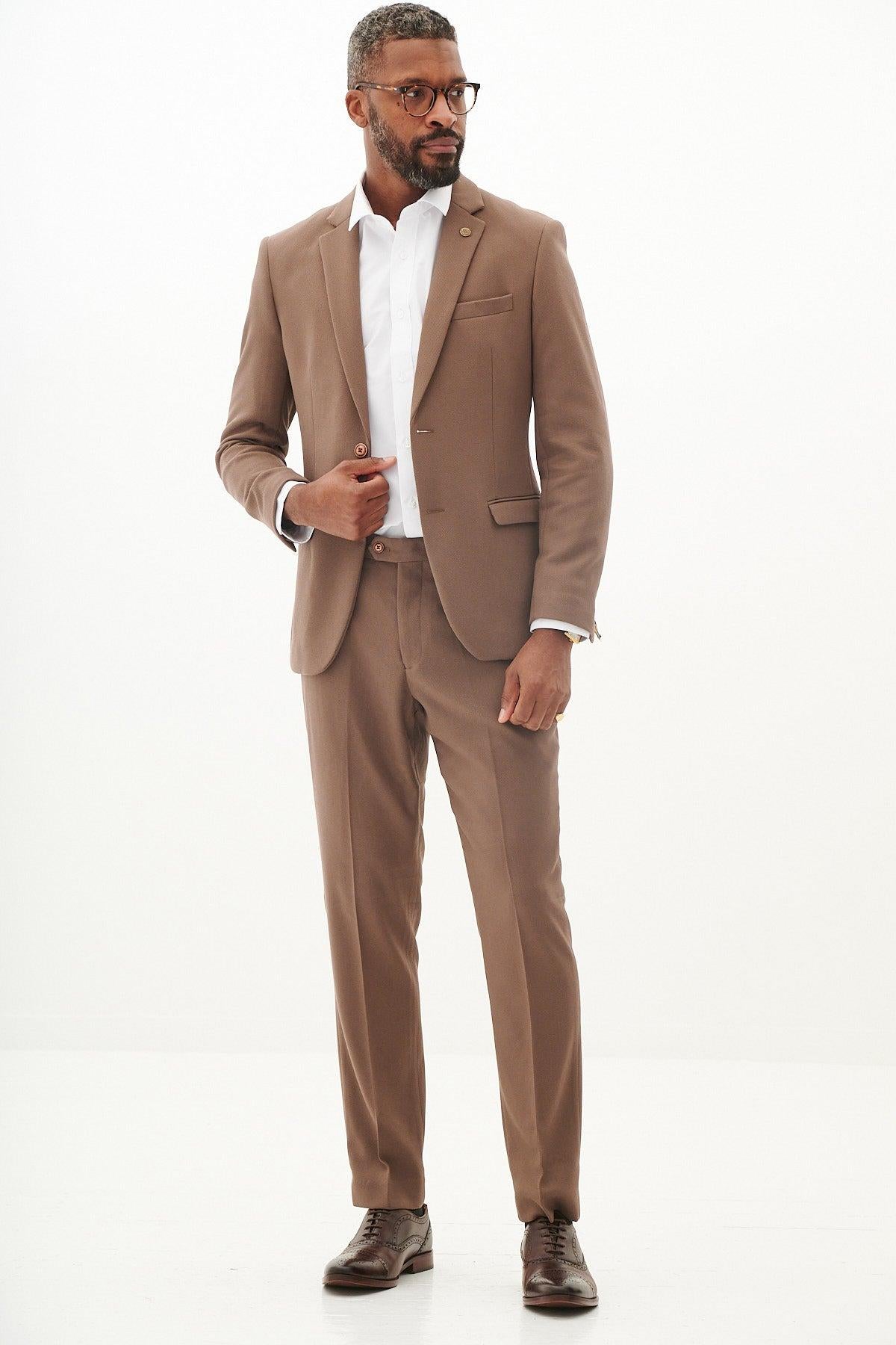A man with short hair, a beard, and glasses wears the Marc Darcy HM5 Tan Tailored Two Piece Suit with a white dress shirt and brown dress shoes, standing against a plain white background.
